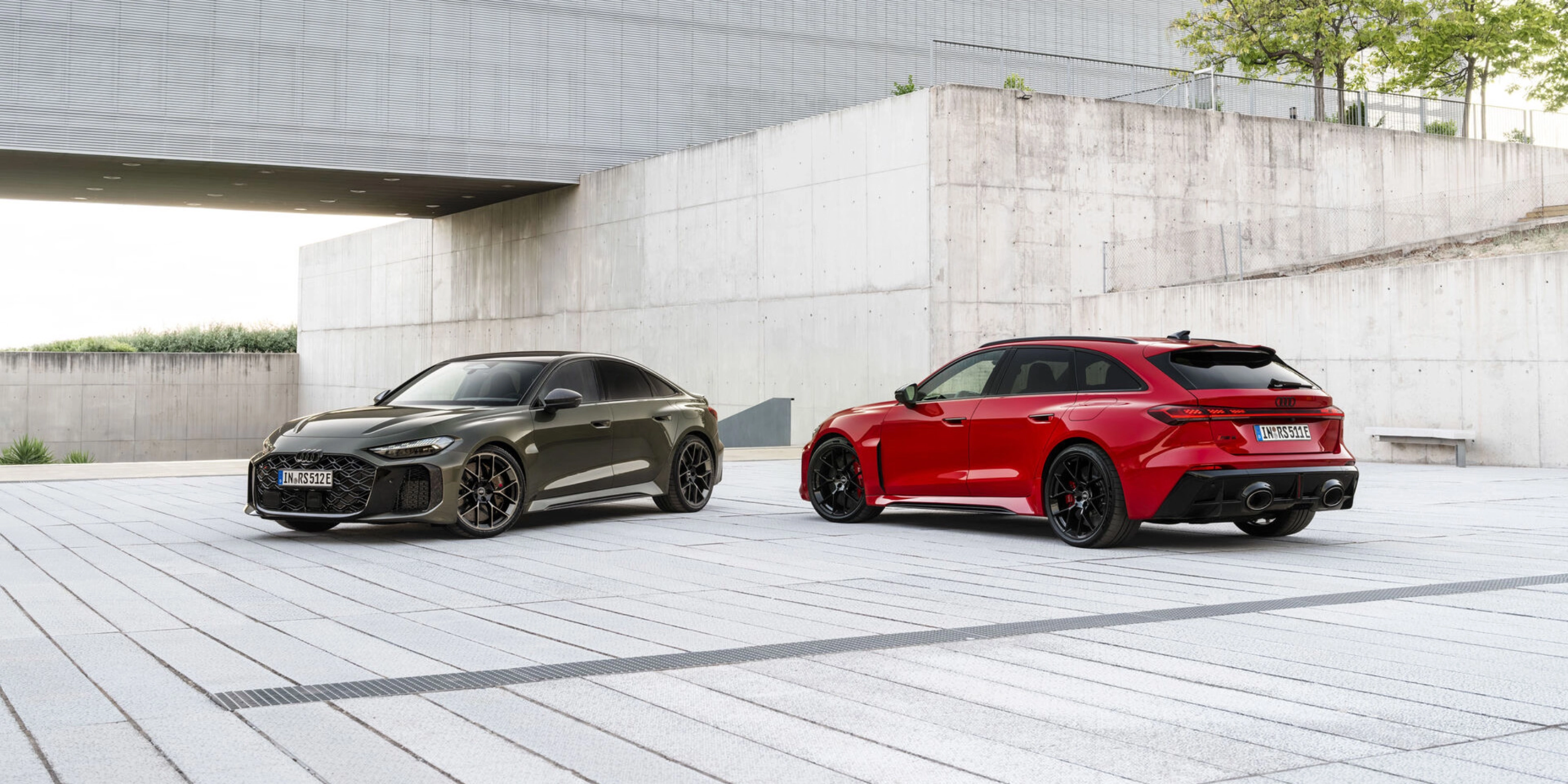 Two Audi performance cars parked in a modern concrete courtyard.