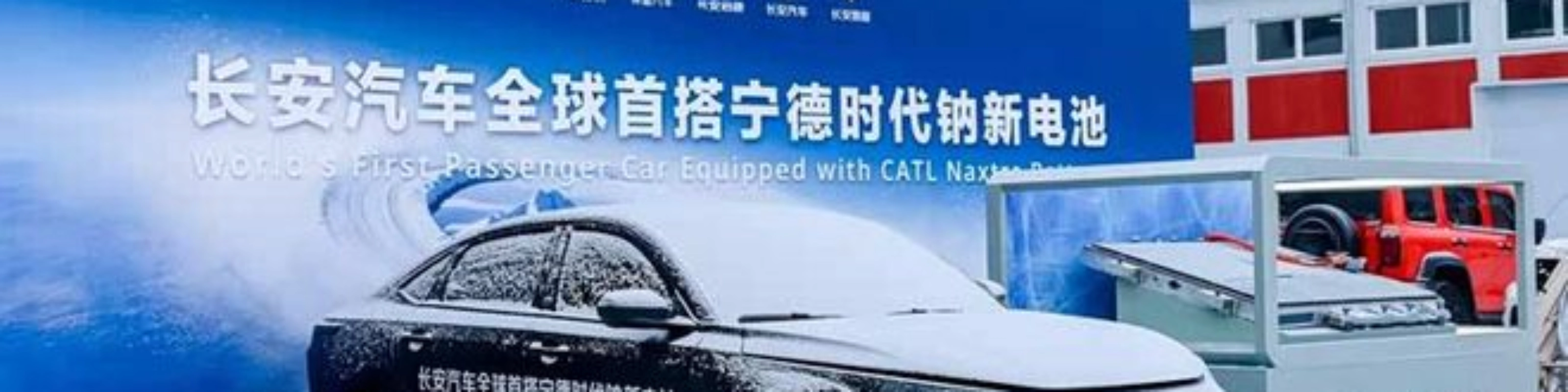 Elektroauto im Schnee vor Messestand mit chinesischem Banner.