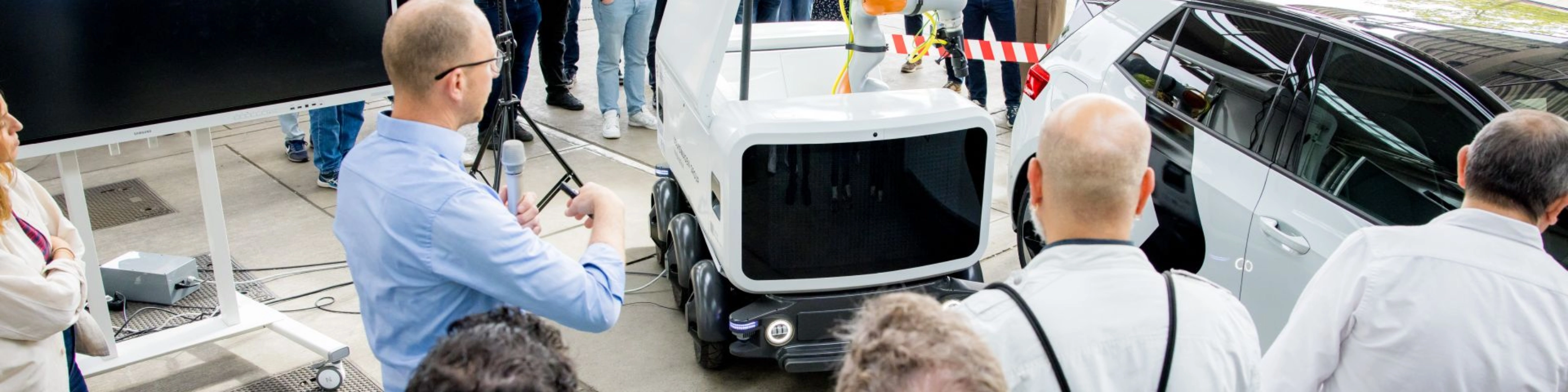 Group of people watching a Volkswagen vehicle demonstration at an outdoor event.