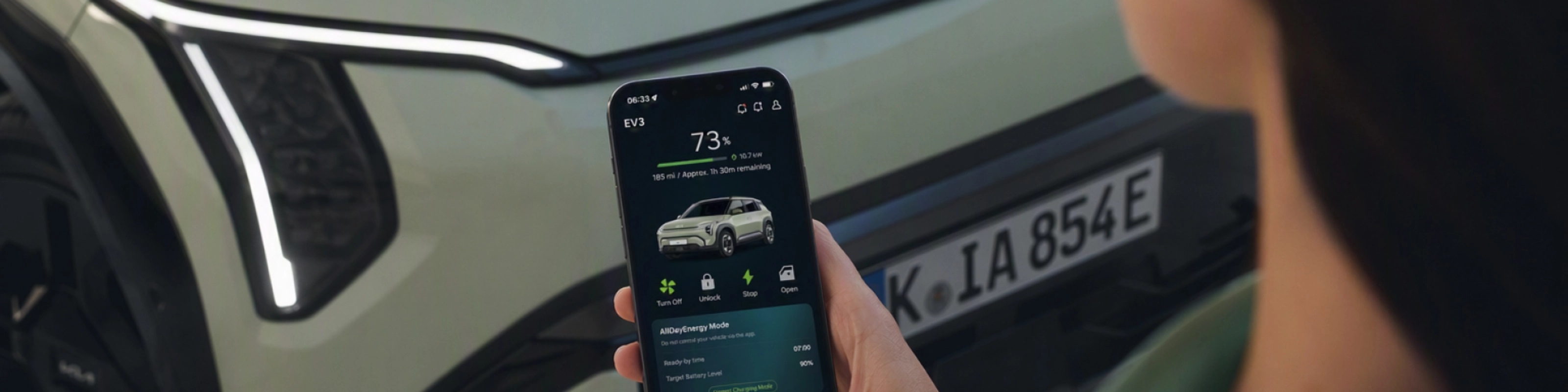 Person nutzt ein Smartphone vor einem Kia-Elektroauto