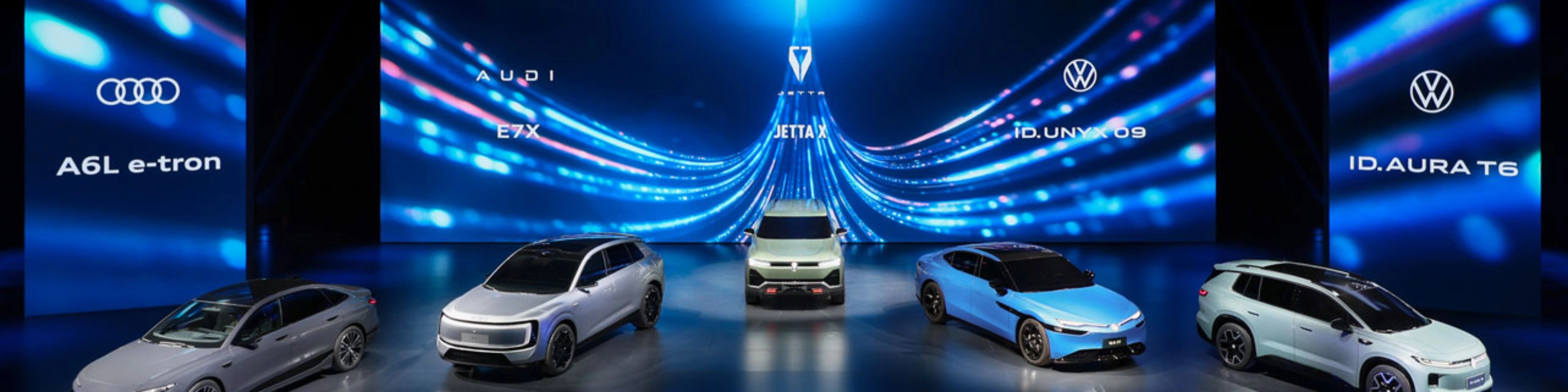 Five cars displayed on a stage with blue digital background.