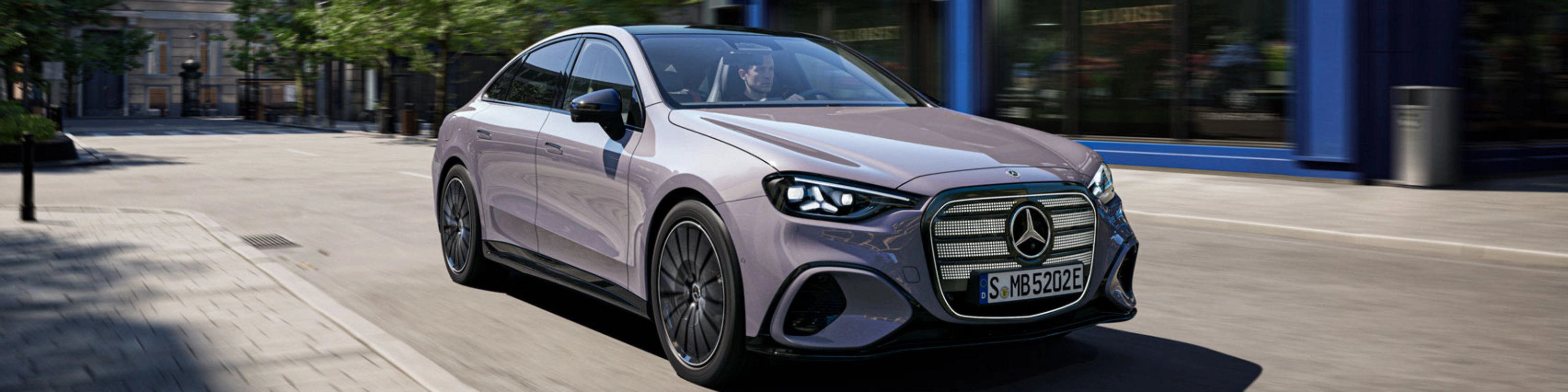 Graue Mercedes-Benz Limousine fährt durch eine Stadtstraße.
