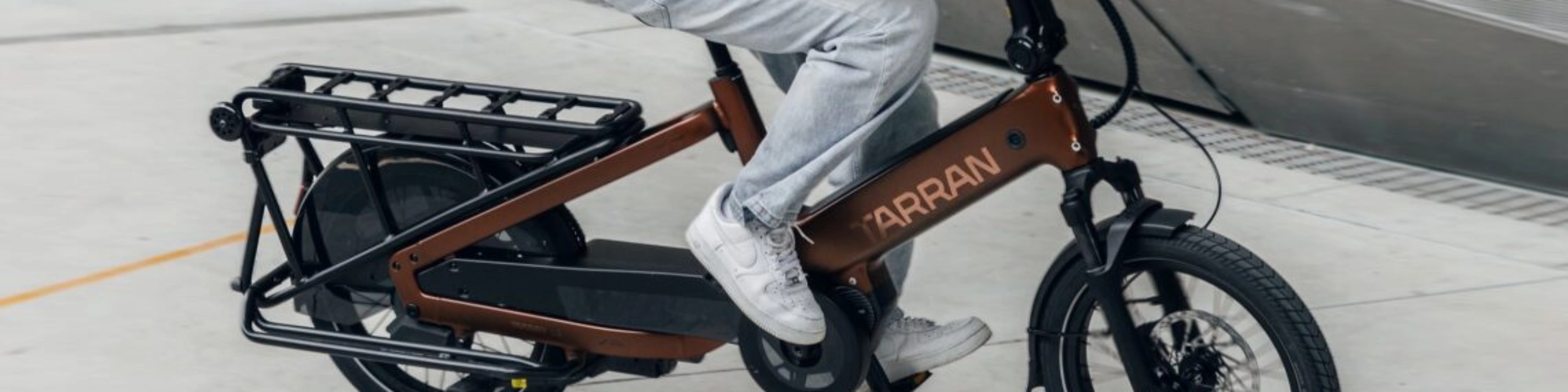 Person fährt ein Tarran Lasten-E-Bike in urbaner Umgebung.