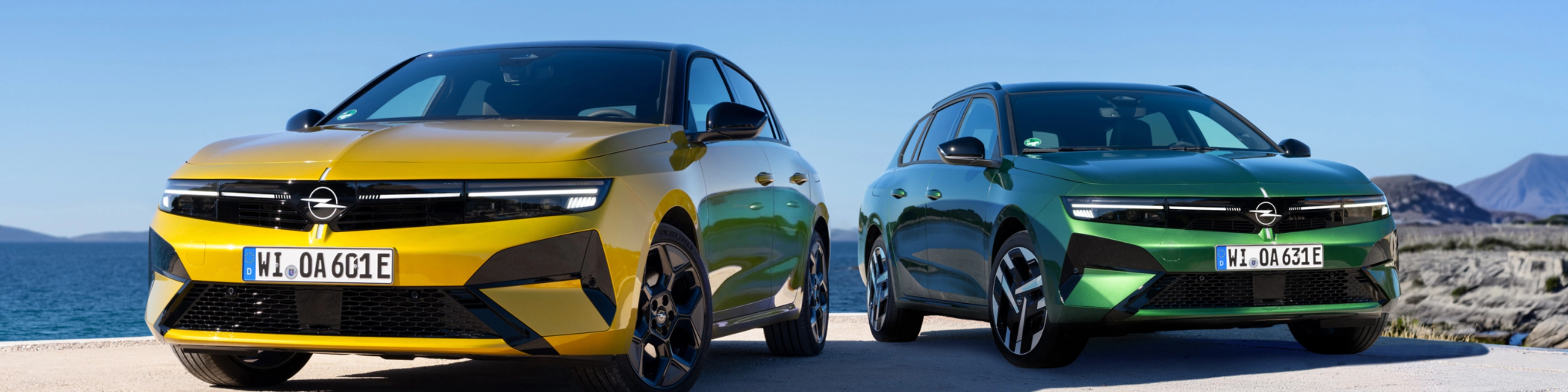 Gelber und grüner Opel stehen nebeneinander am Meer.