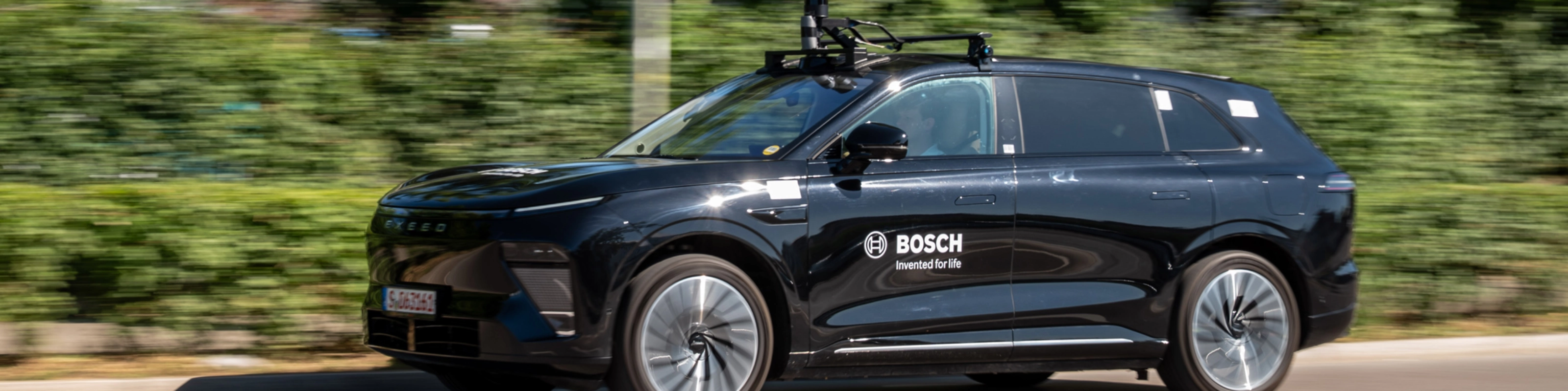 Schwarzer Bosch-Test-SUV mit Dachsensoren fährt auf Straße.