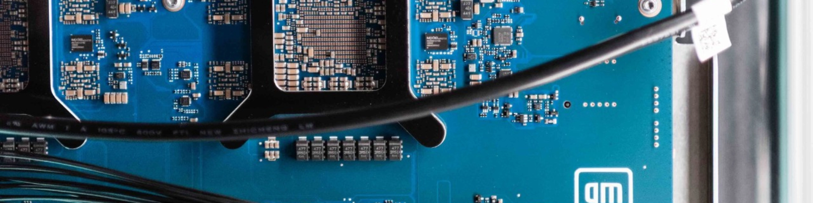 Close-up of a blue General Motors circuit board with electronic components and connectors.