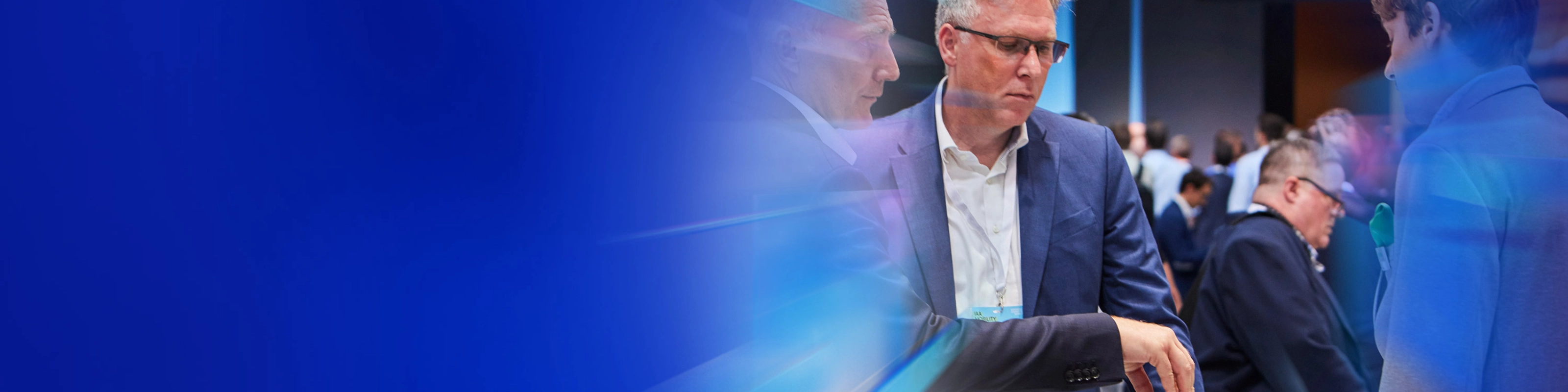 Drei Männer begutachten ein technisches Bauteil auf einer Messe beim IAA Summit.