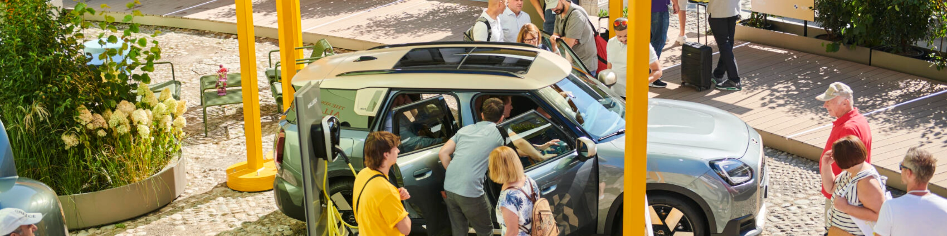 People at an outdoor event looking at a concept car on display.