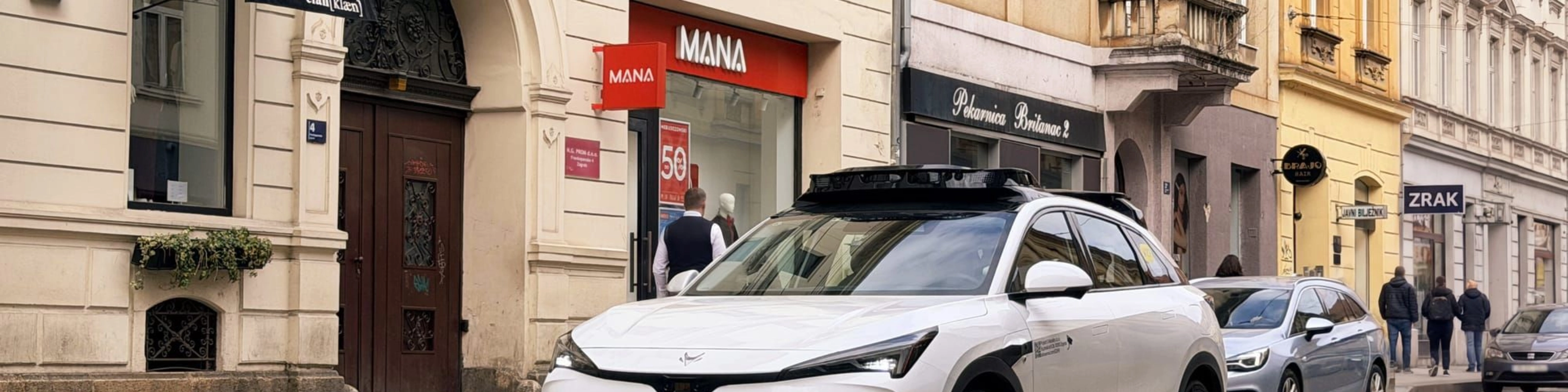 Autonomes Testfahrzeug fährt durch eine Stadtstraße mit Geschäften
