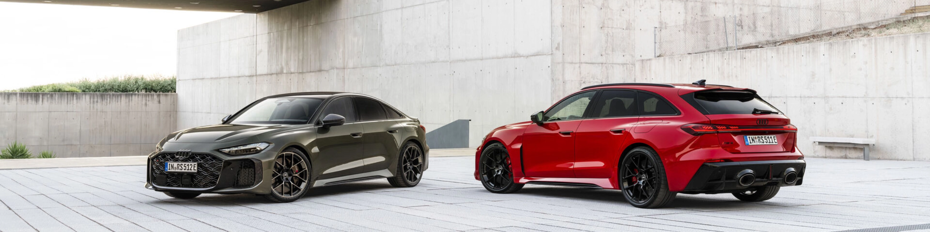 Two Audi performance cars parked in a modern concrete courtyard.