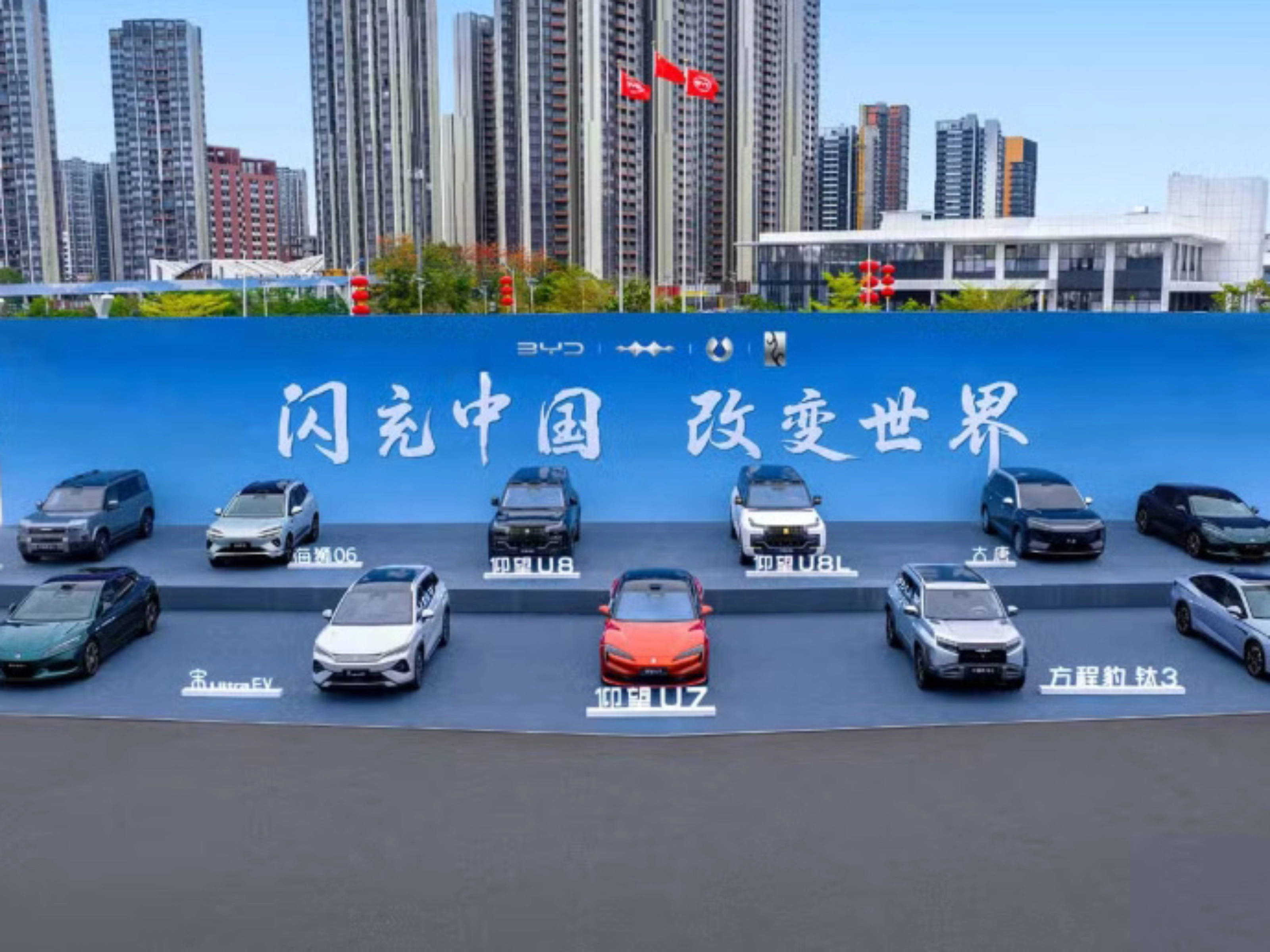 BYD vehicles displayed on a stage outdoors in front of a large promotional backdrop.