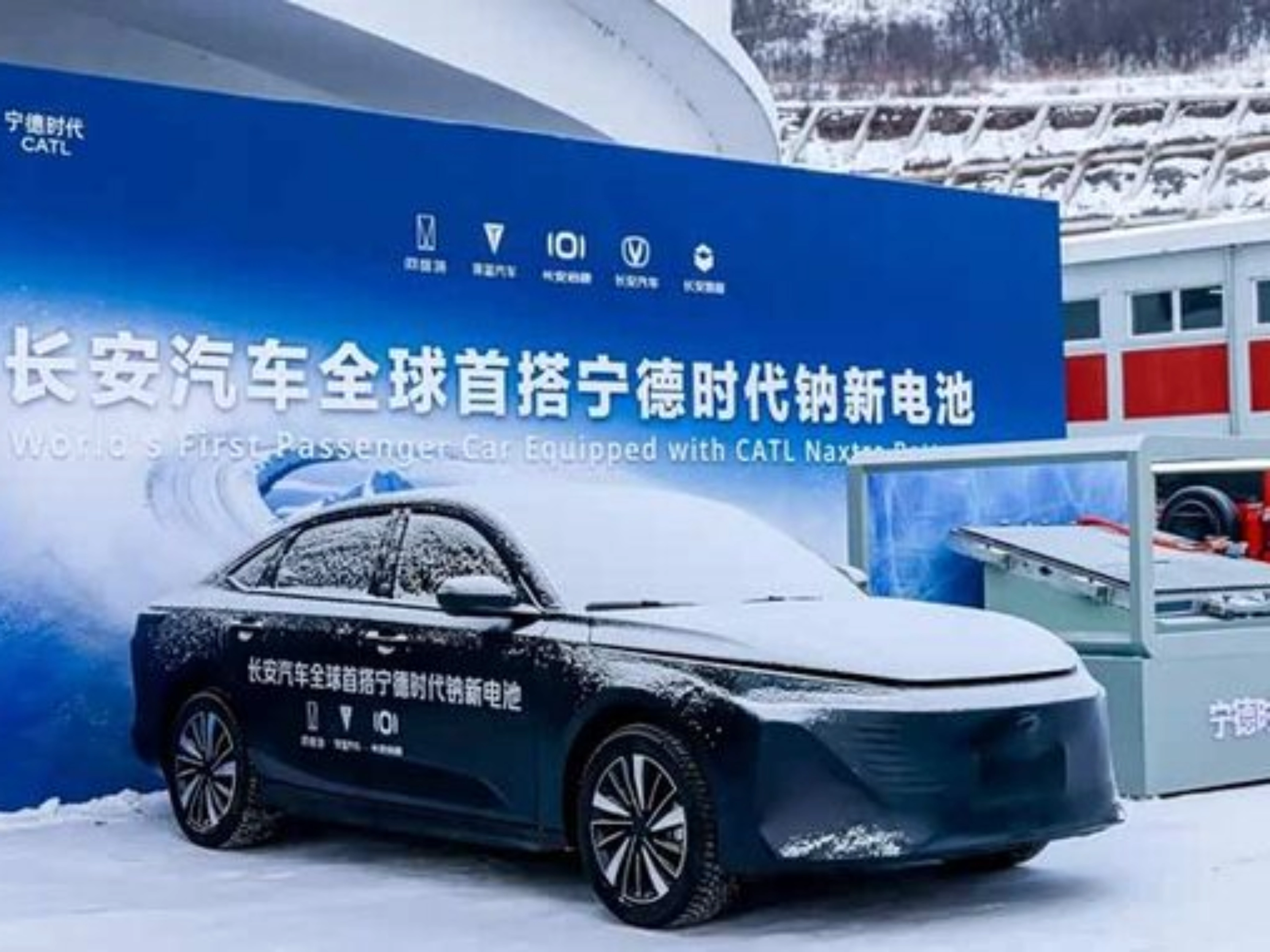 Elektroauto im Schnee vor Messestand mit chinesischem Banner.