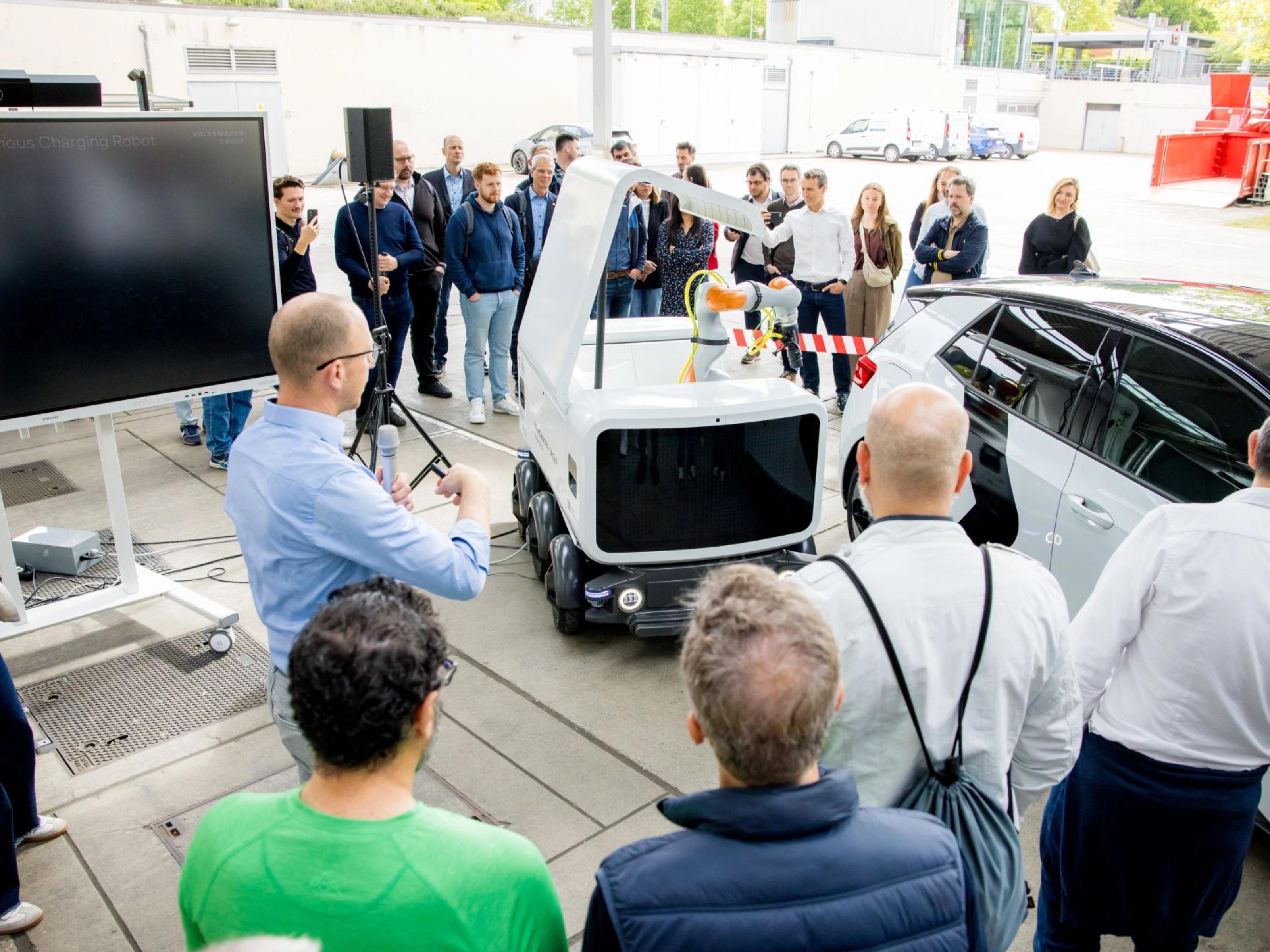 Group of people watching a Volkswagen vehicle demonstration at an outdoor event.