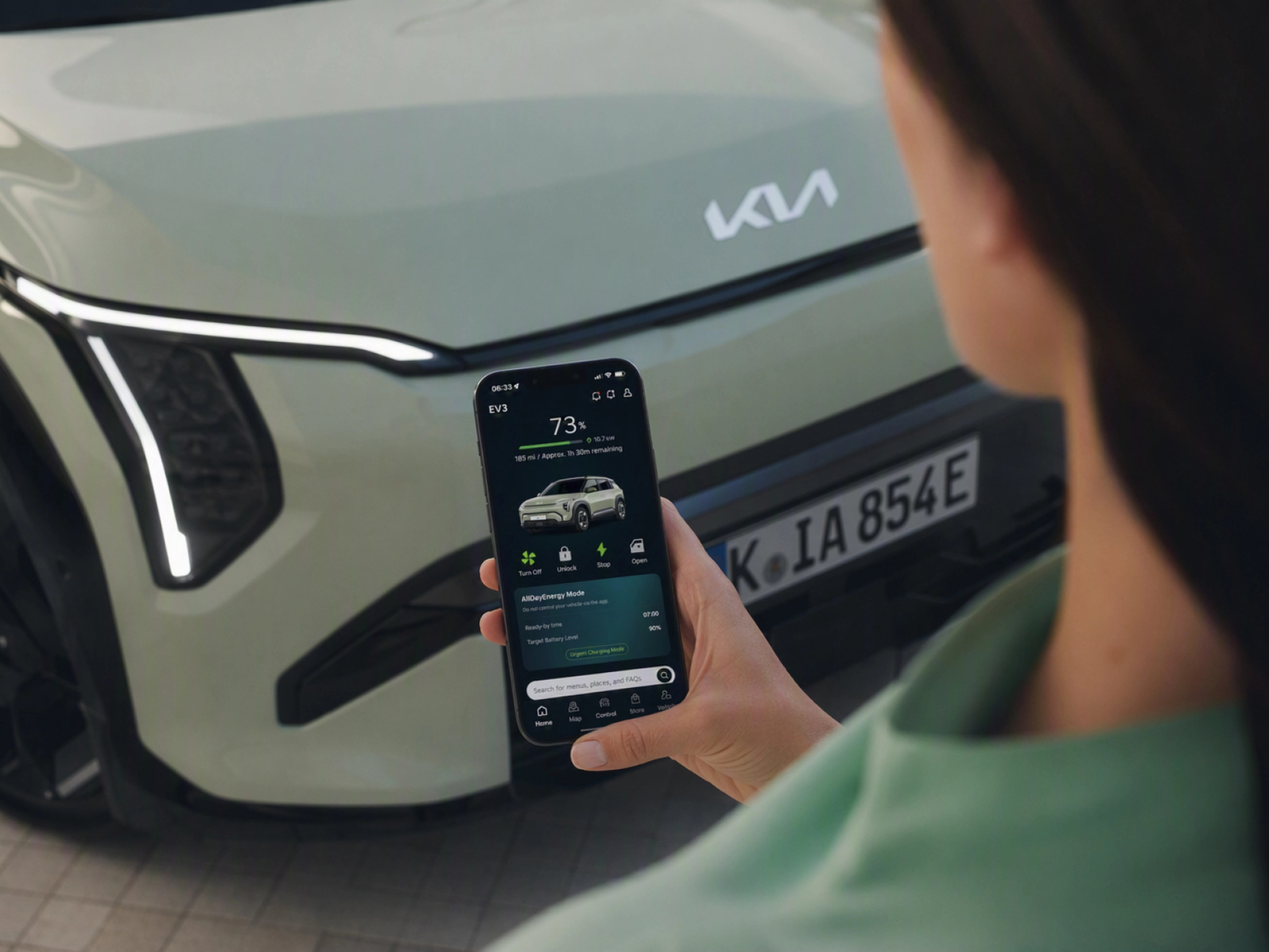 Person nutzt ein Smartphone vor einem Kia-Elektroauto