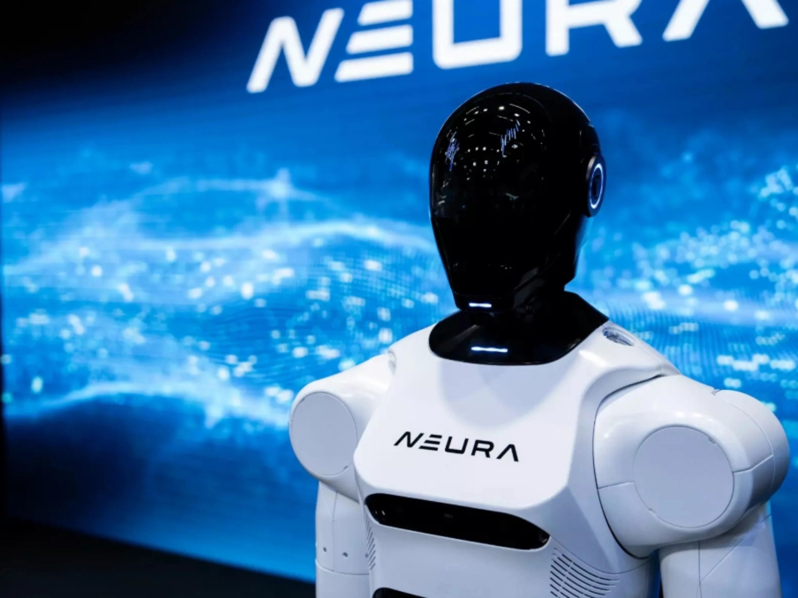 Humanoider Roboter mit schwarzem Kopf und weißem Körper vor NEURA-Logo und digitalem Hintergrund.