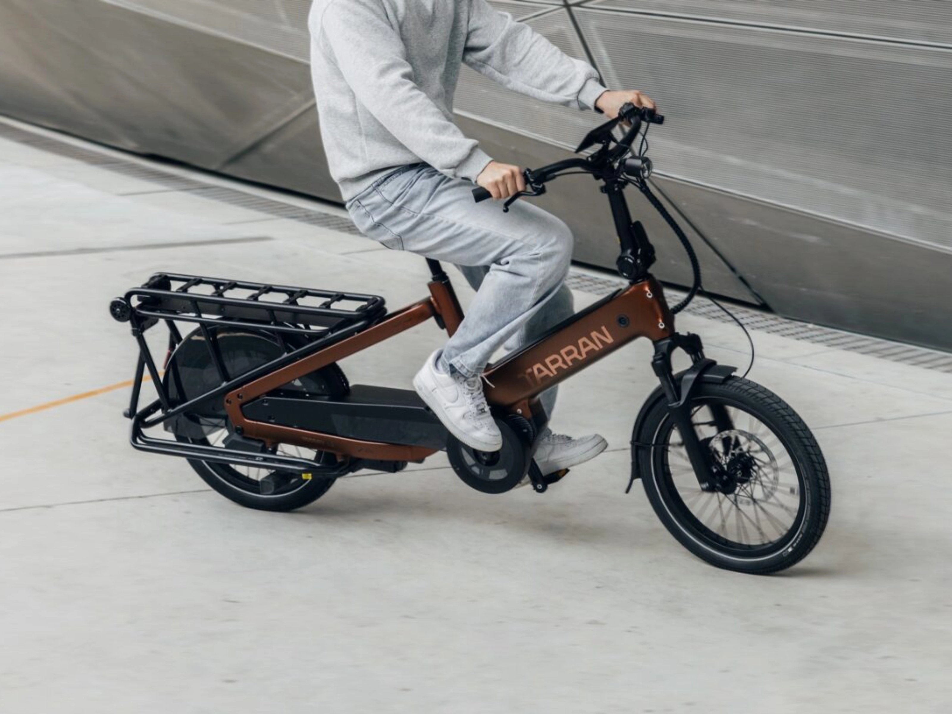 Person fährt ein Tarran Lasten-E-Bike in urbaner Umgebung.