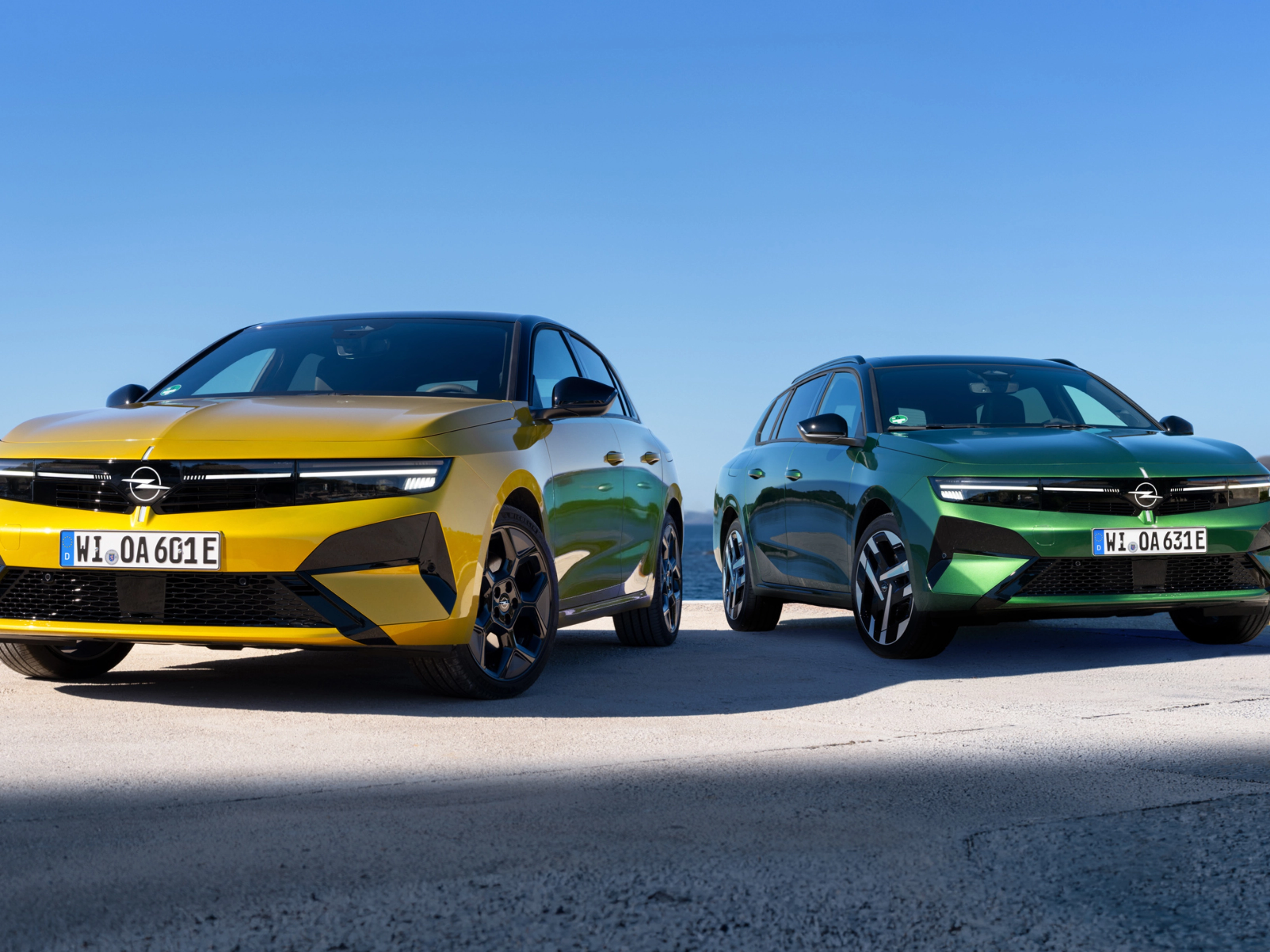 Gelber und grüner Opel stehen nebeneinander am Meer.