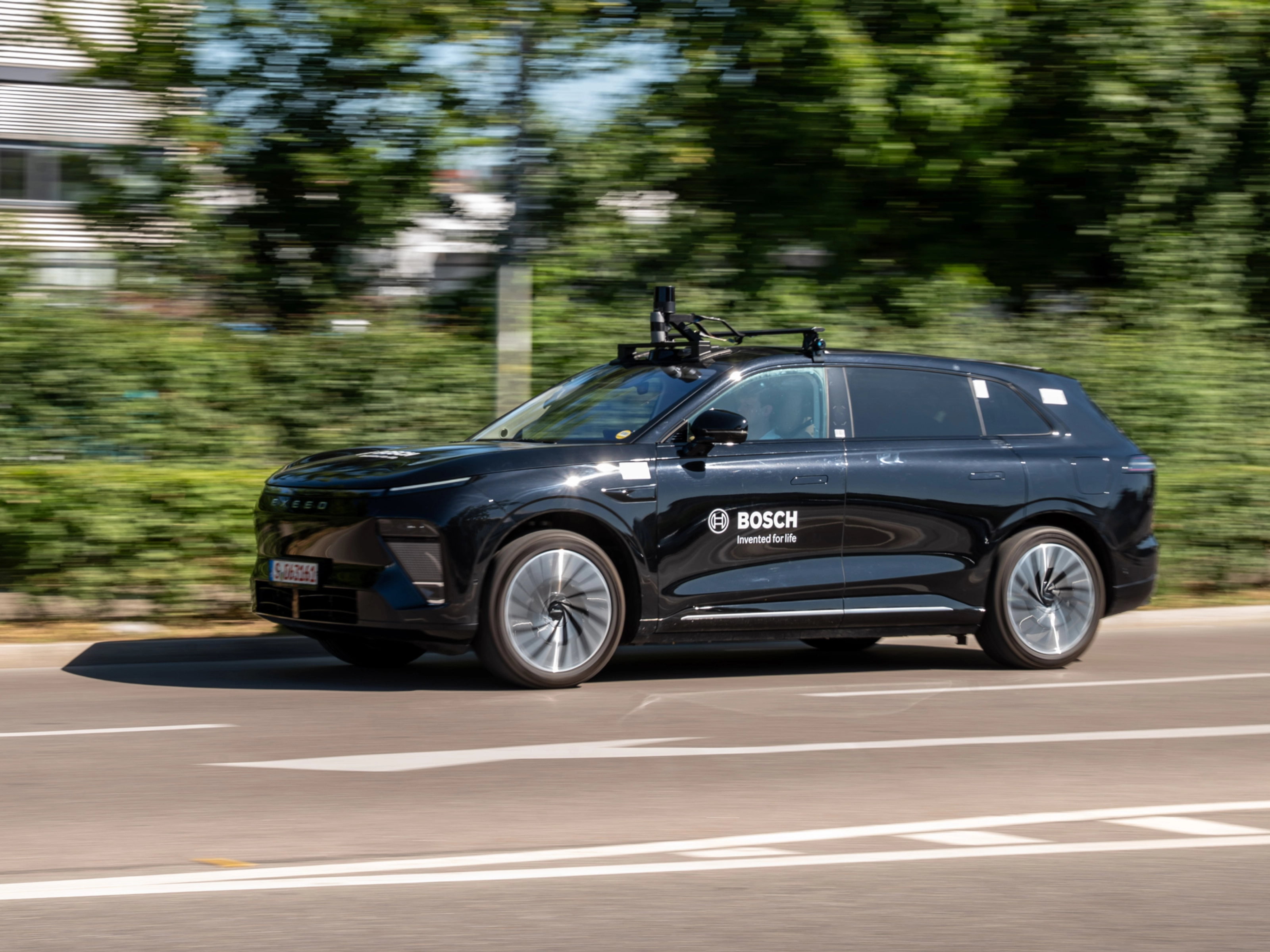 Schwarzer Bosch-Test-SUV mit Dachsensoren fährt auf Straße.