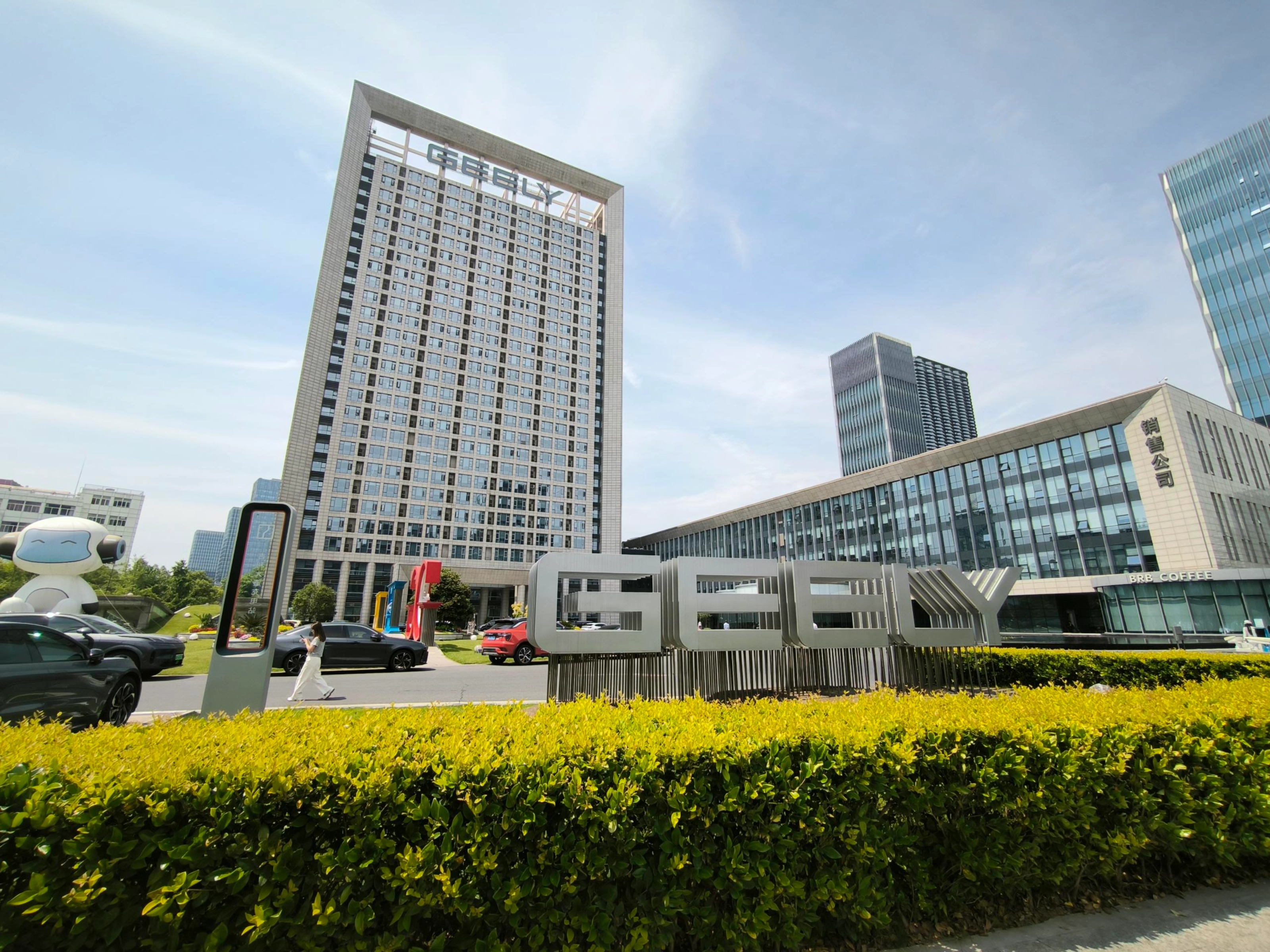 Geely-Logo vor einem modernen Bürogebäude.