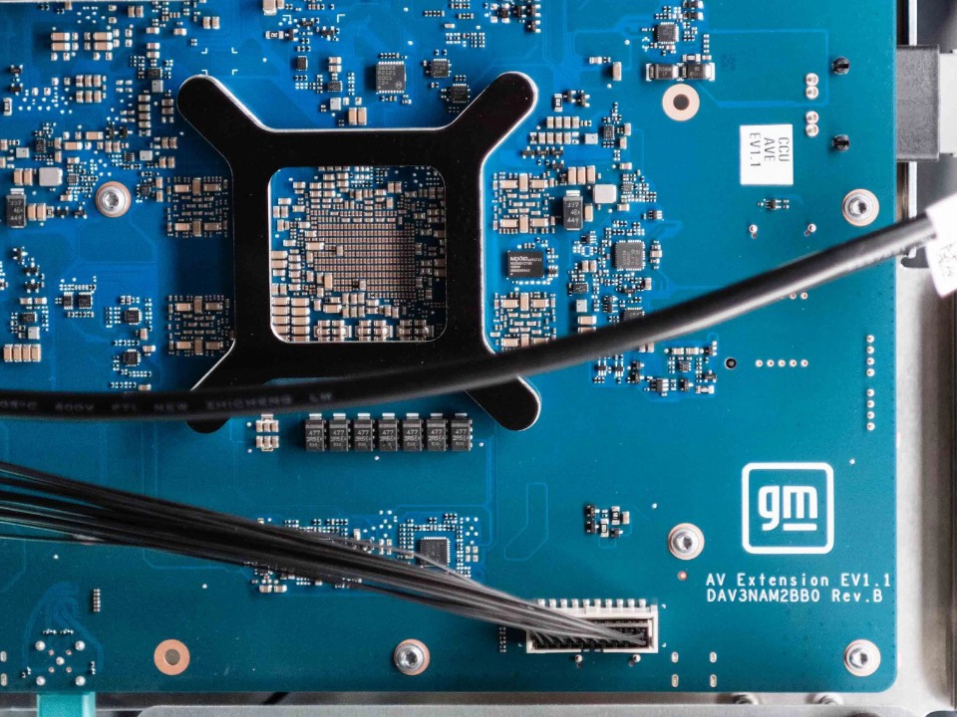Close-up of a blue General Motors circuit board with electronic components and connectors.