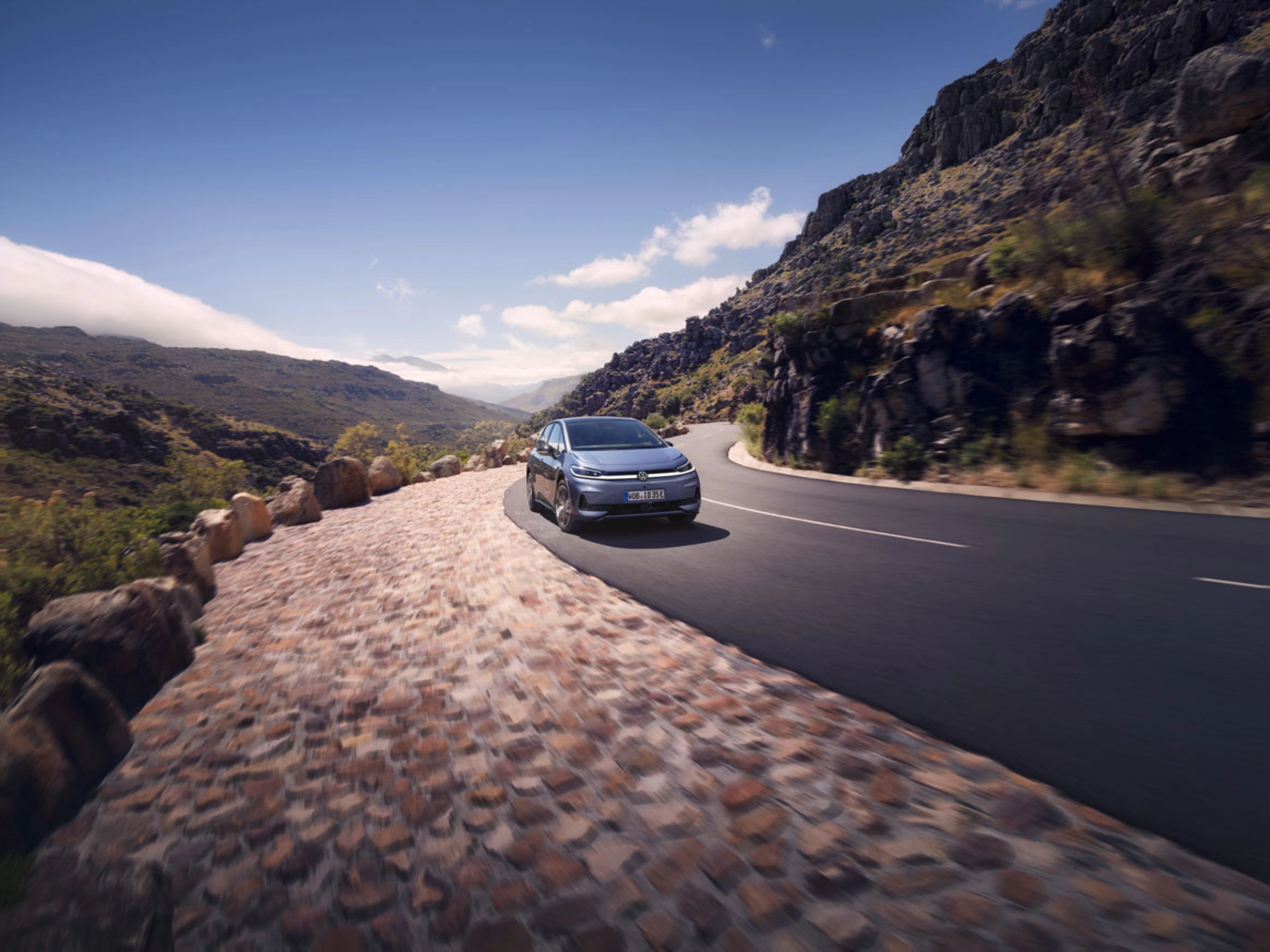 Volkswagen fährt auf einer Bergstraße mit felsiger Landschaft