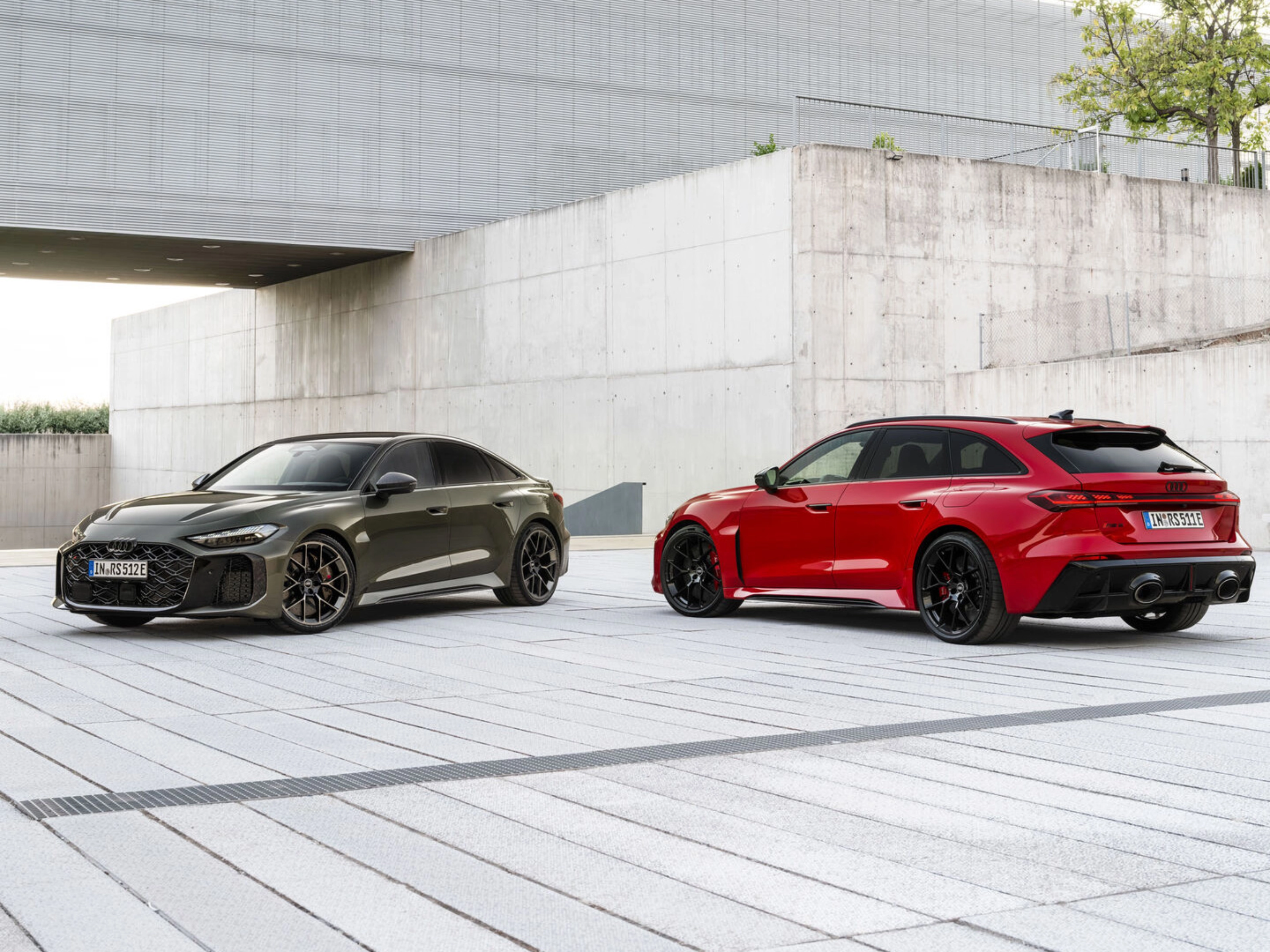 Two Audi performance cars parked in a modern concrete courtyard.