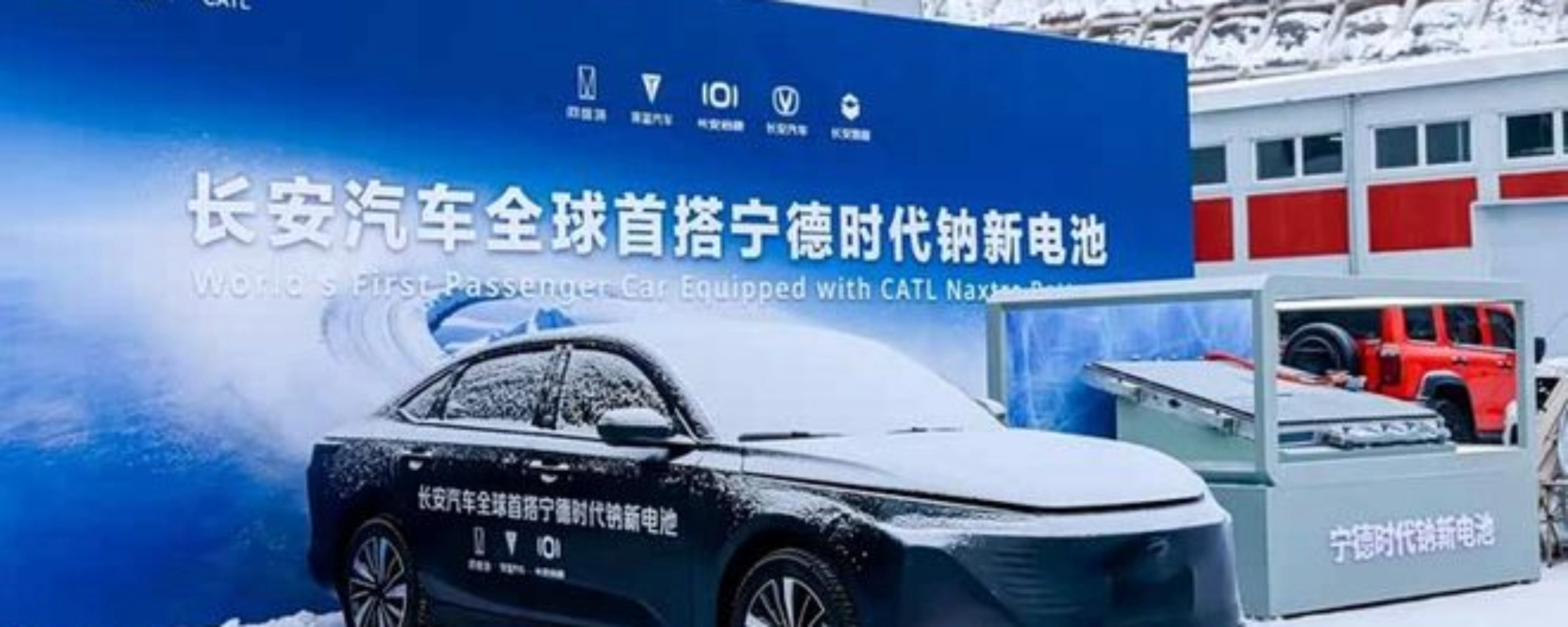 Elektroauto im Schnee vor Messestand mit chinesischem Banner.
