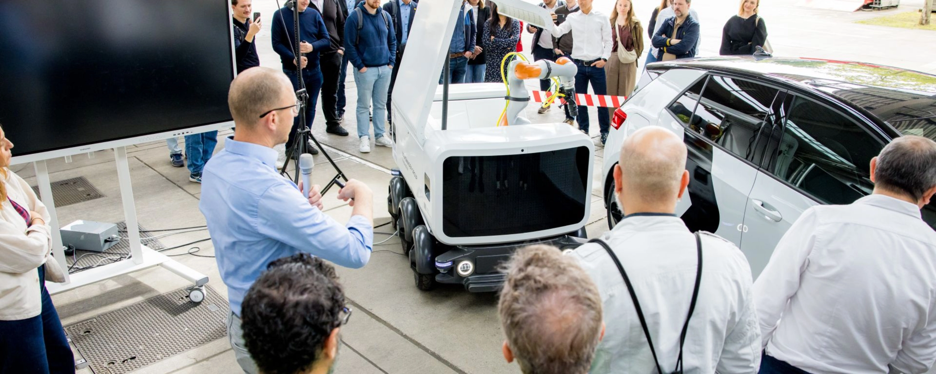 Group of people watching a Volkswagen vehicle demonstration at an outdoor event.