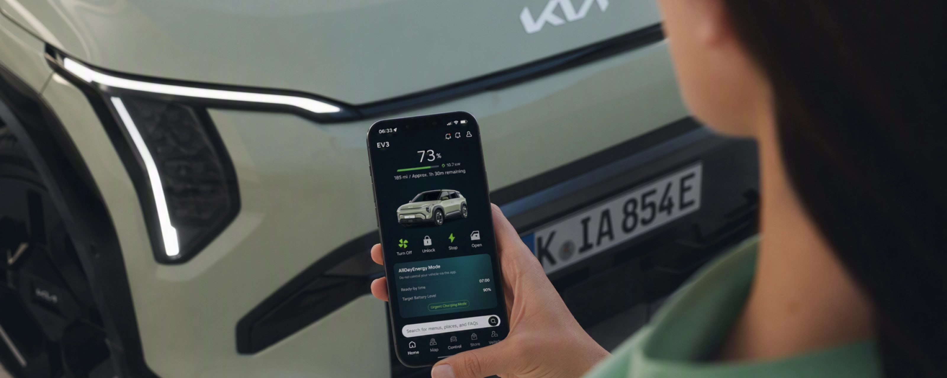 Person nutzt ein Smartphone vor einem Kia-Elektroauto