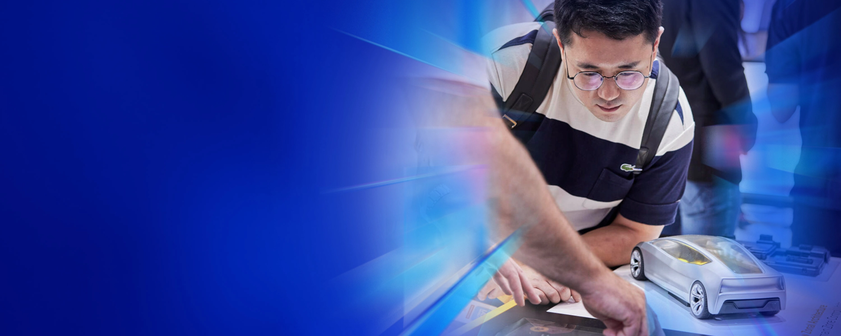Mann betrachtet ein futuristisches Automodell und einen Touchscreen auf einer Technologiemesse.