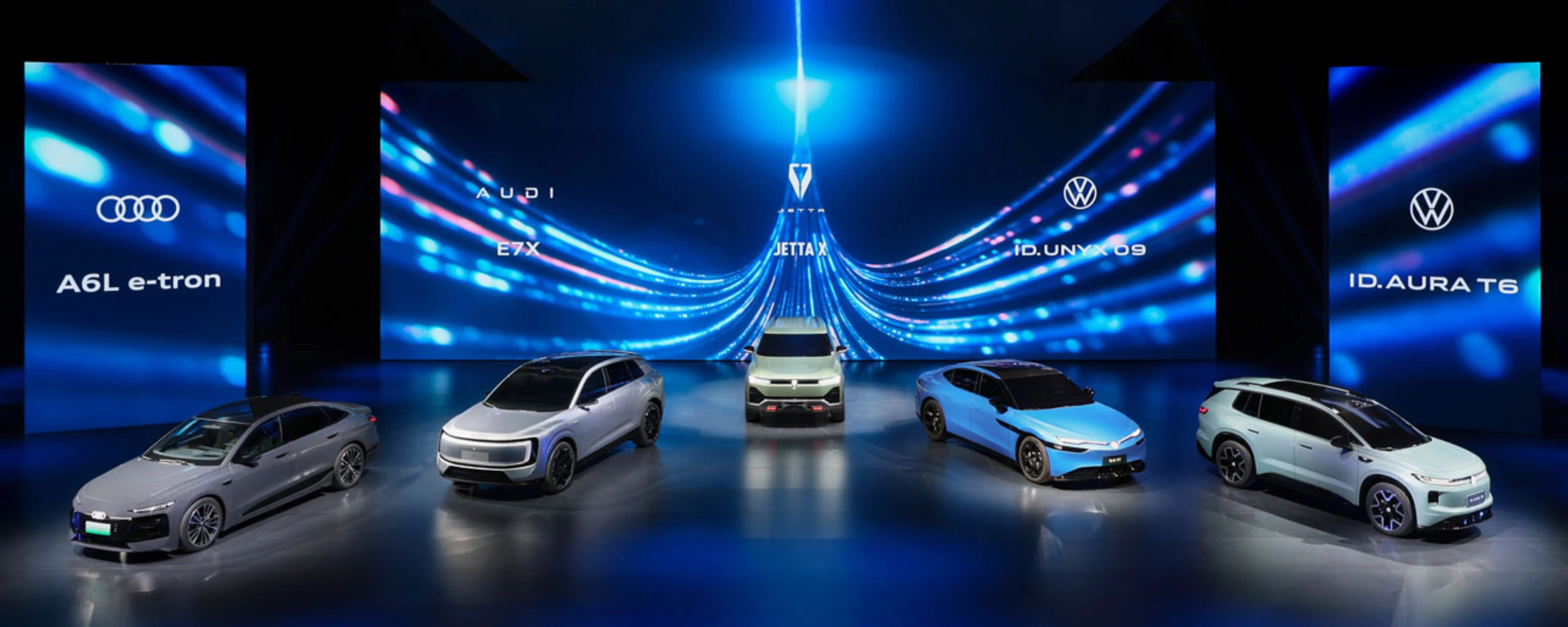 Five cars displayed on a stage with blue digital background.