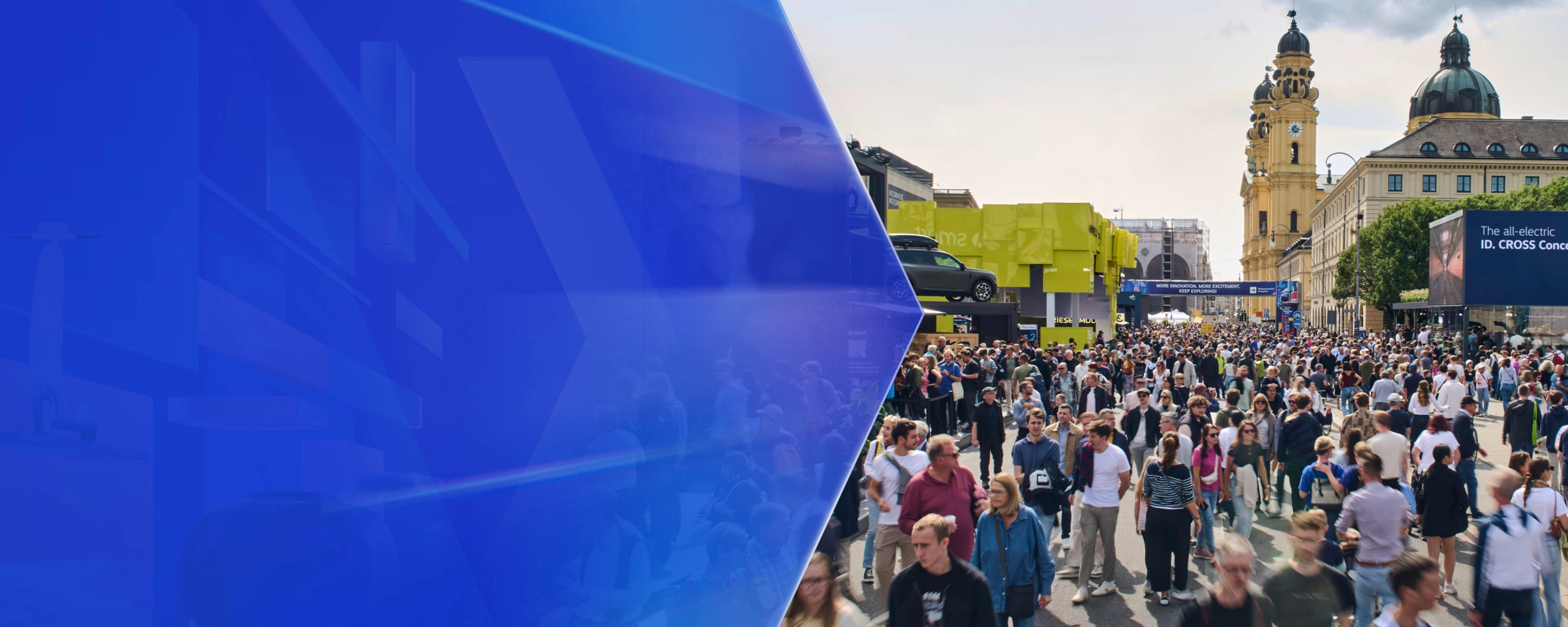 Große Menschenmenge auf einer Mobilitätsmesse im Freien mit Ausstellungsständen und Altbauten.