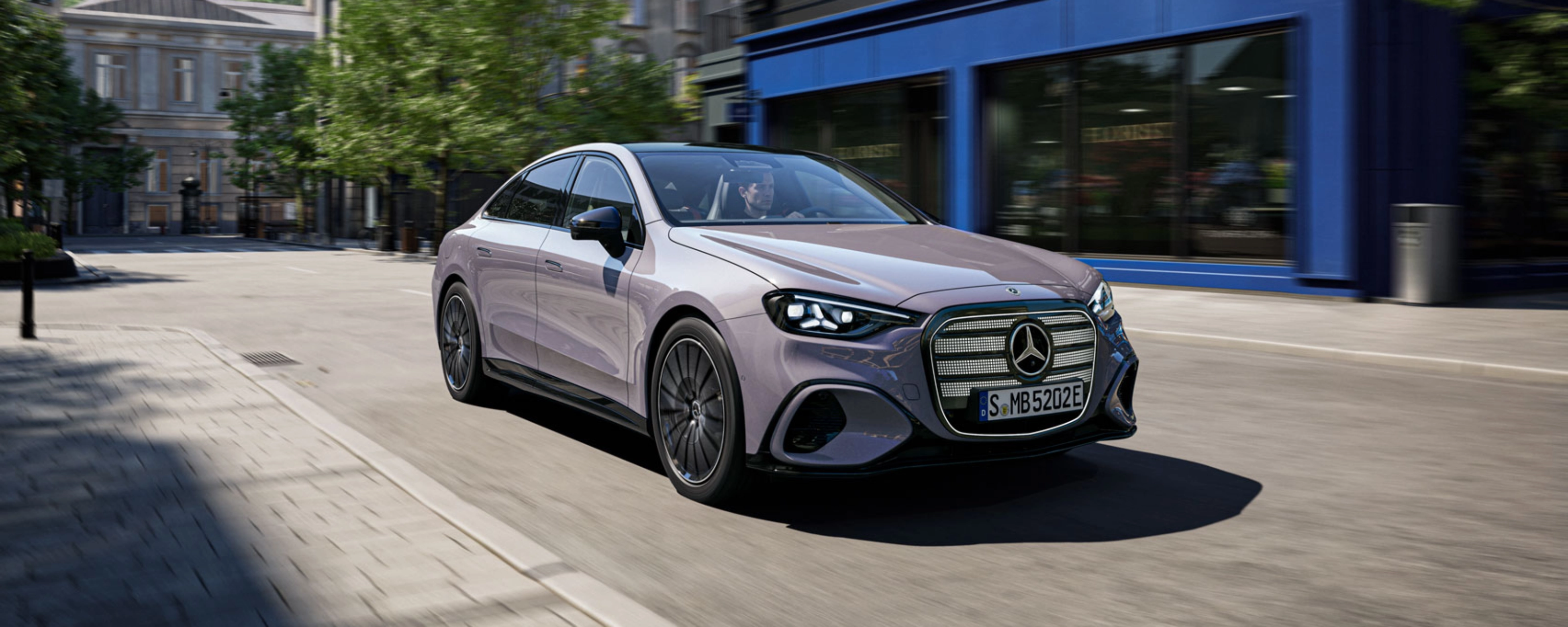 Graue Mercedes-Benz Limousine fährt durch eine Stadtstraße.