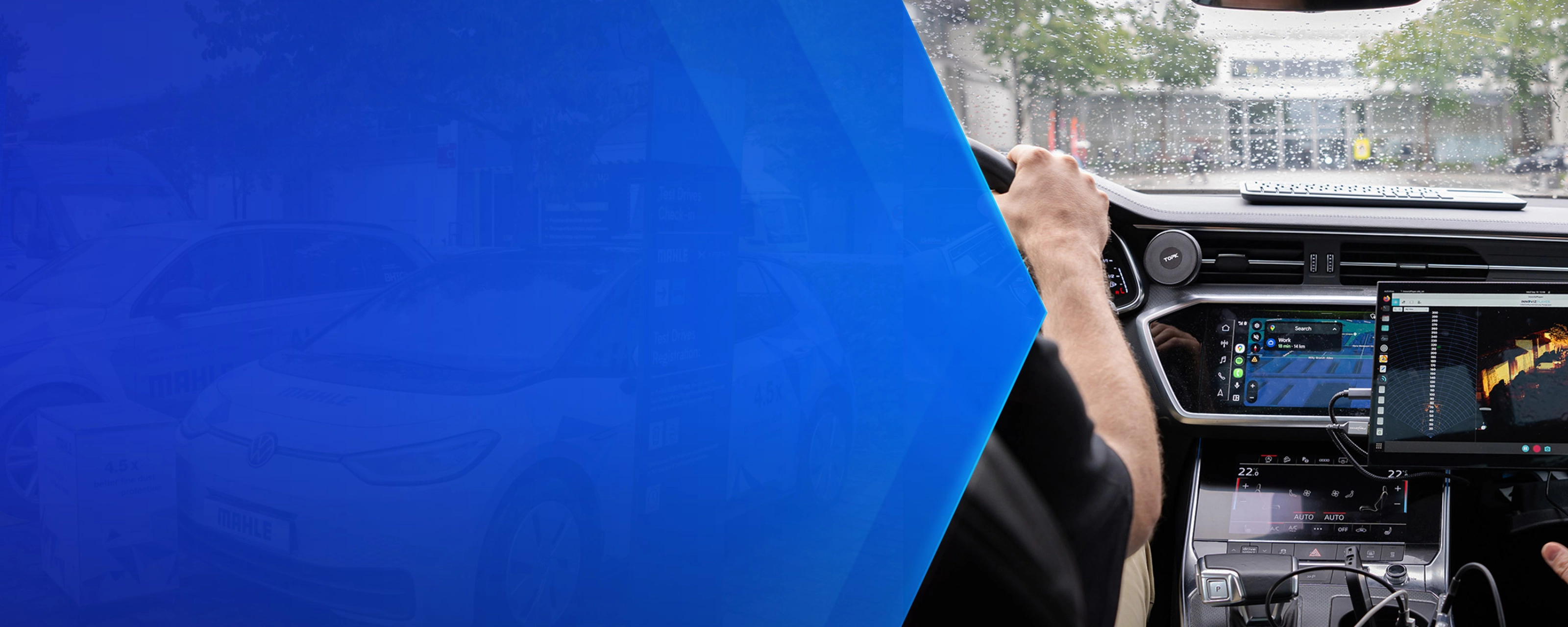 Driver tests in-car technology with navigation and monitoring screens during rainy conditions.