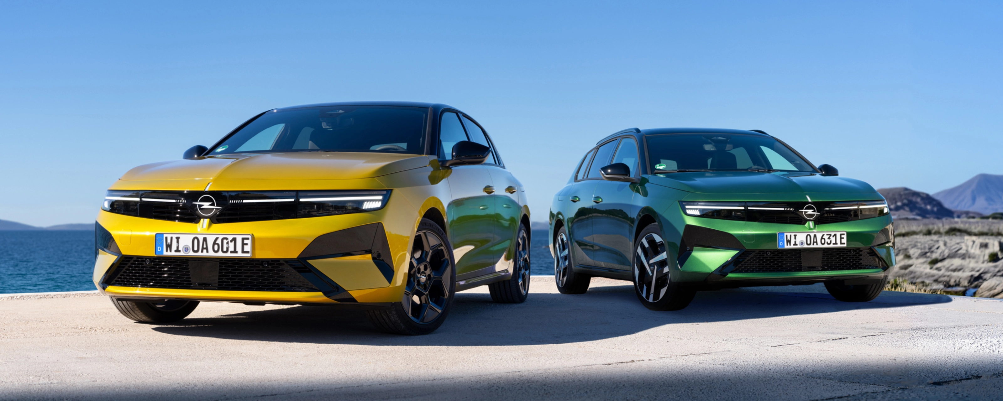 Gelber und grüner Opel stehen nebeneinander am Meer.