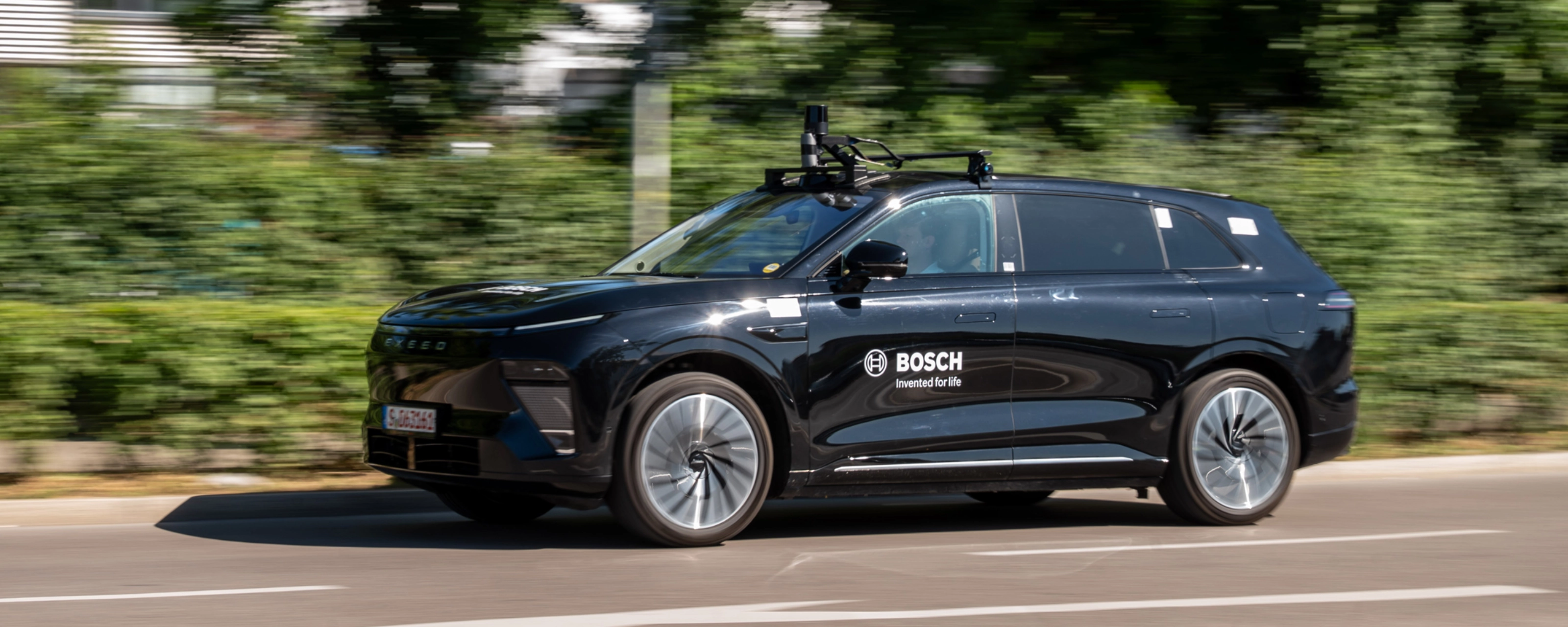 Schwarzer Bosch-Test-SUV mit Dachsensoren fährt auf Straße.