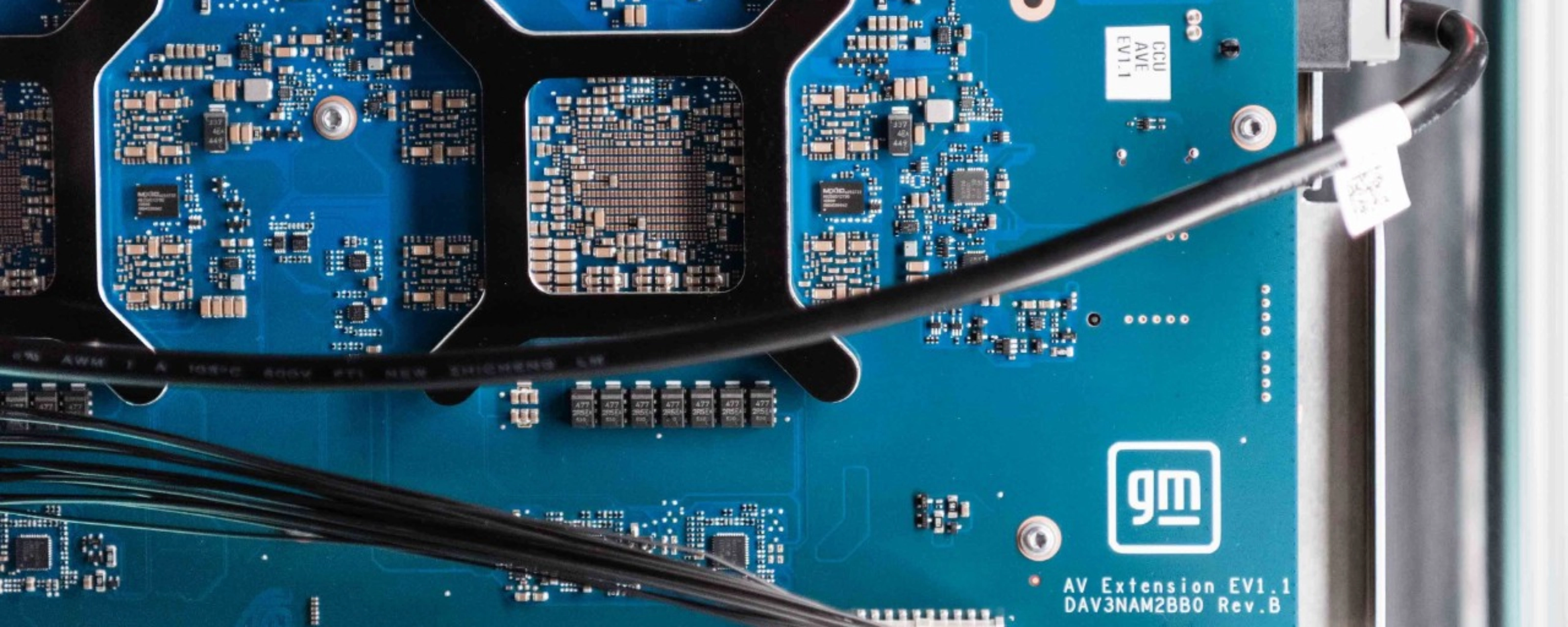 Close-up of a blue General Motors circuit board with electronic components and connectors.