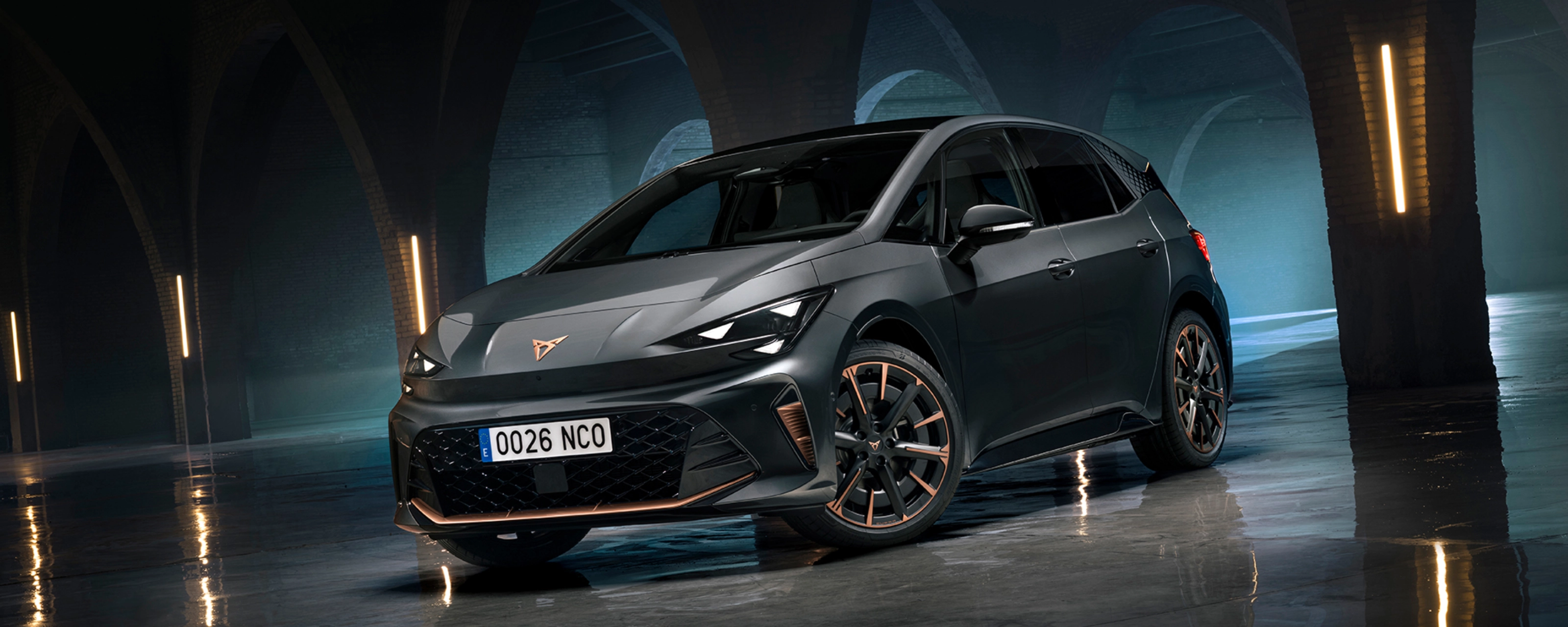 CUPRA Elektroauto steht in einer dunklen Halle mit Bögen und spiegelndem Boden.