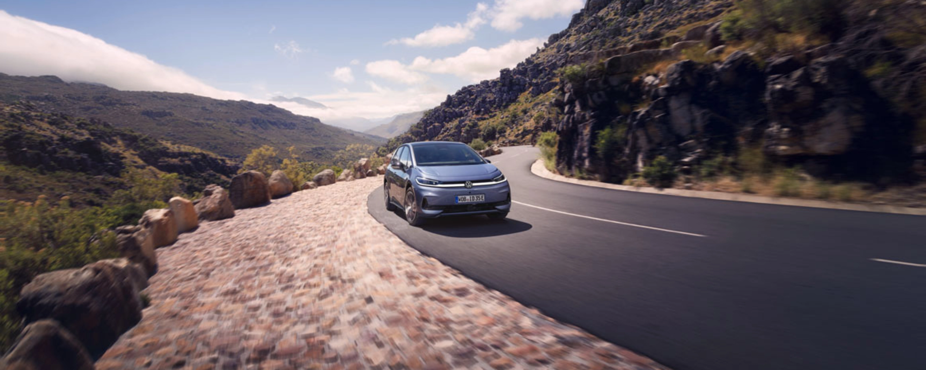 Volkswagen fährt auf einer Bergstraße mit felsiger Landschaft