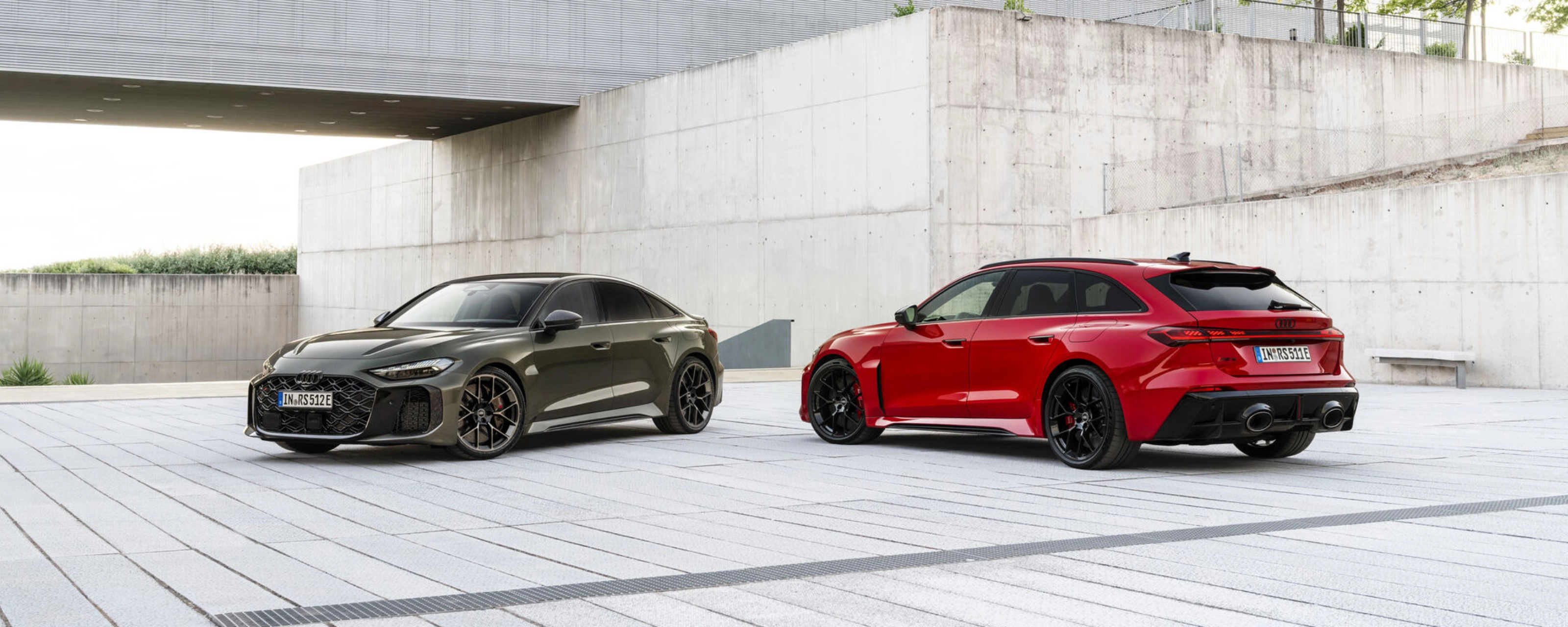 Two Audi performance cars parked in a modern concrete courtyard.