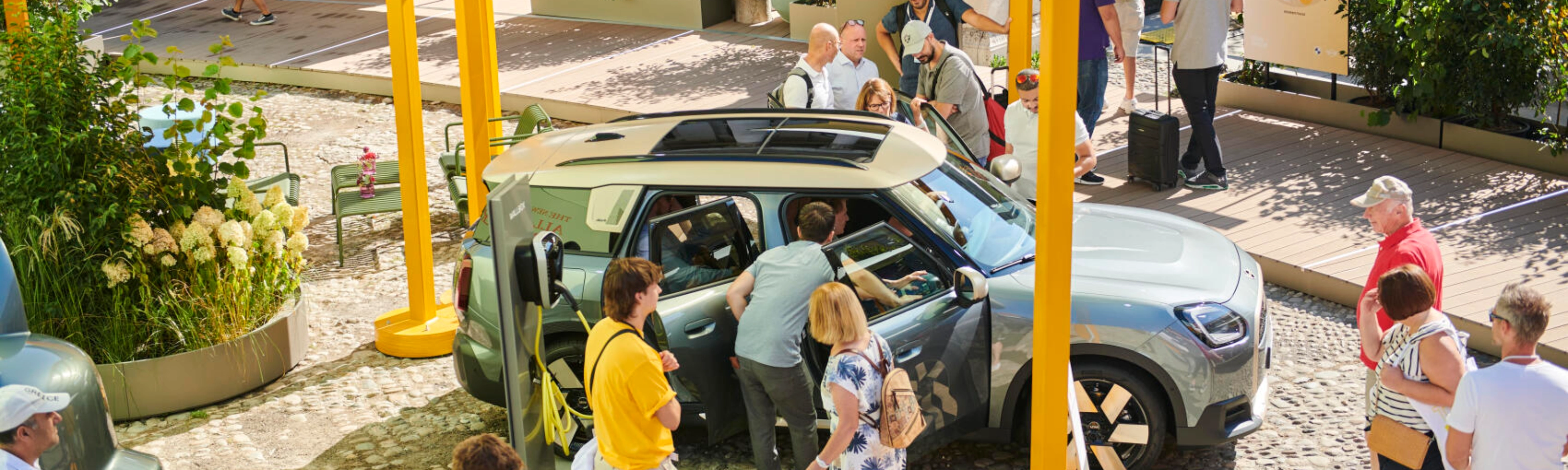 People at an outdoor event looking at a concept car on display.