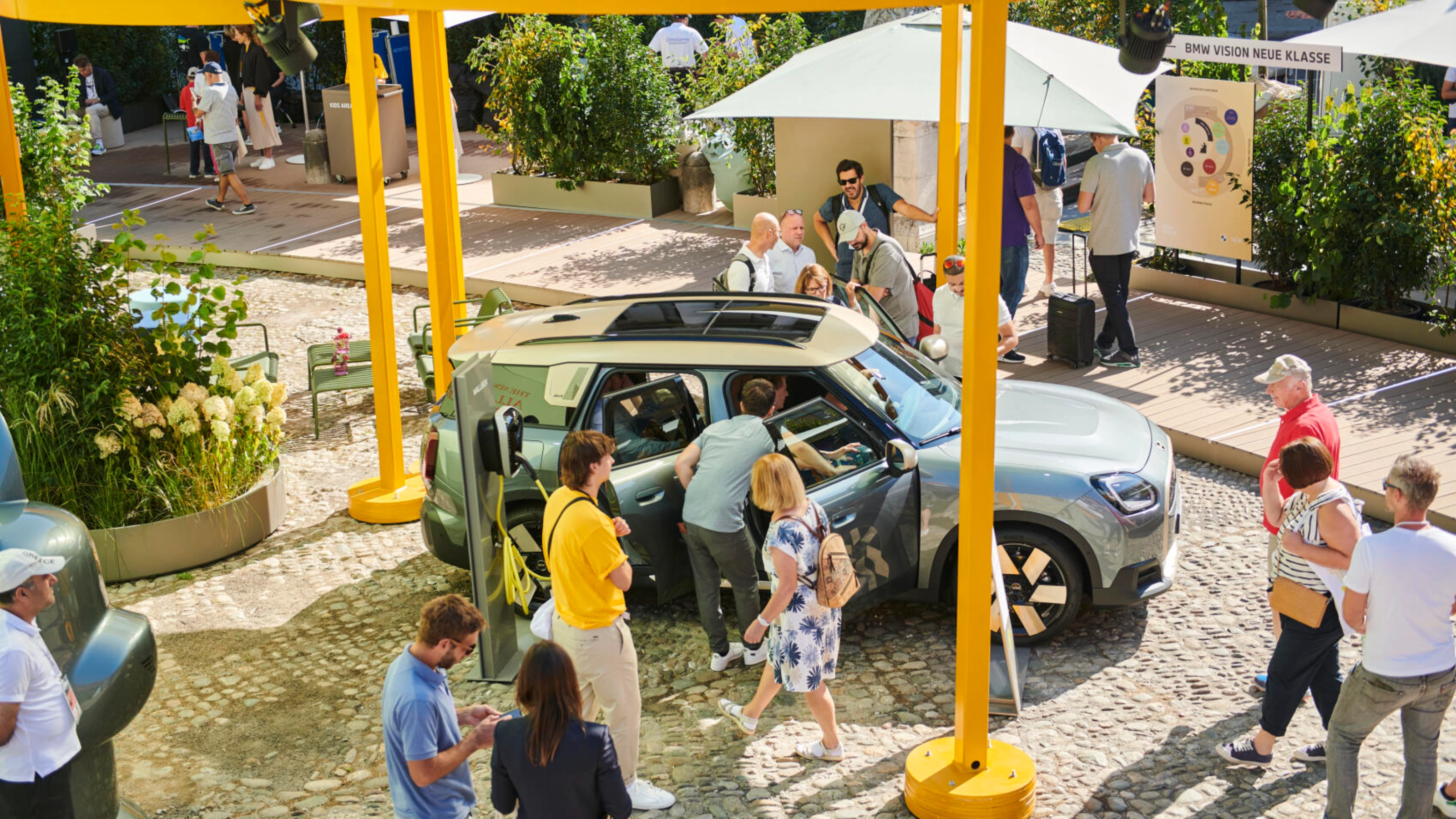 People at an outdoor event looking at a concept car on display.