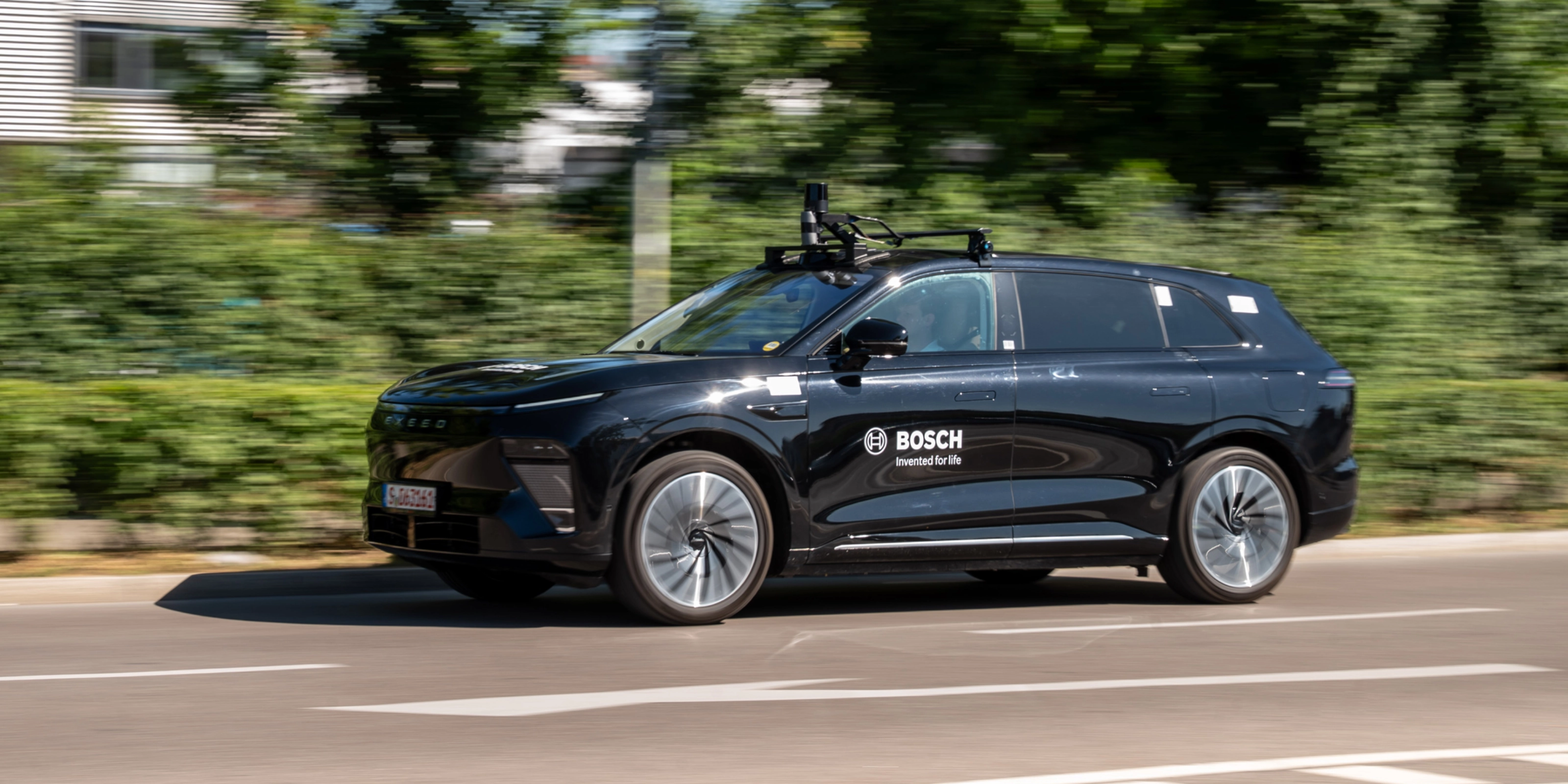 Schwarzer Bosch-Test-SUV mit Dachsensoren fährt auf Straße.