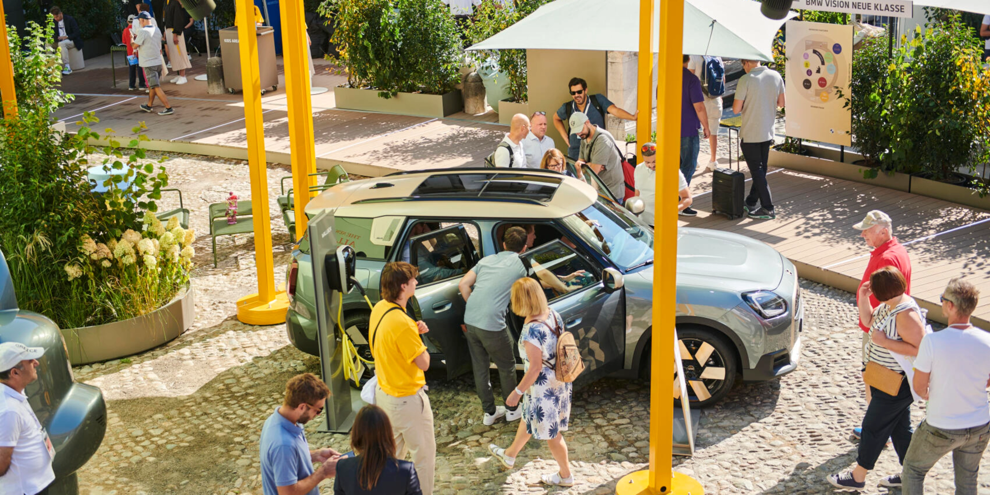 People at an outdoor event looking at a concept car on display.