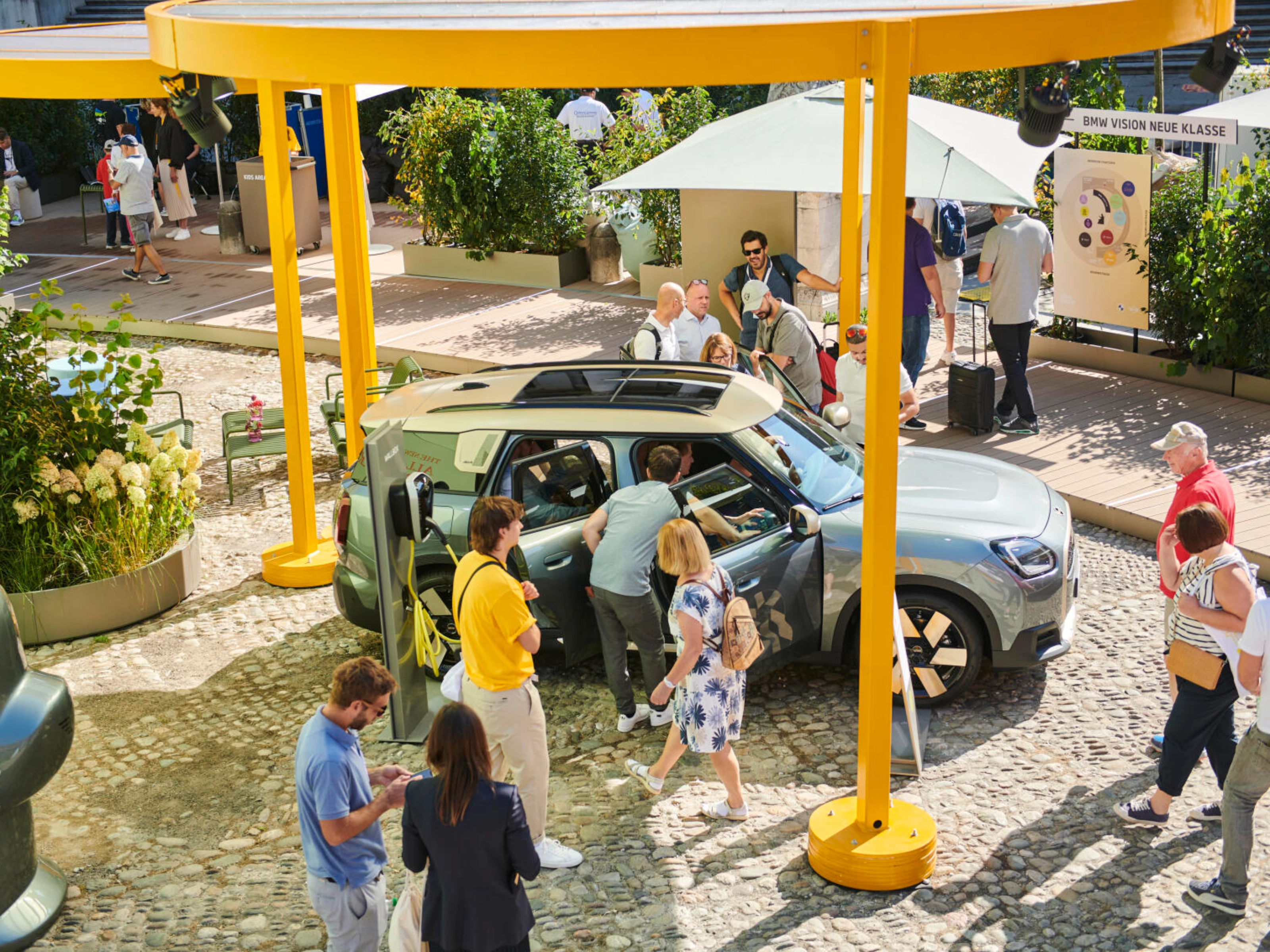 People at an outdoor event looking at a concept car on display.