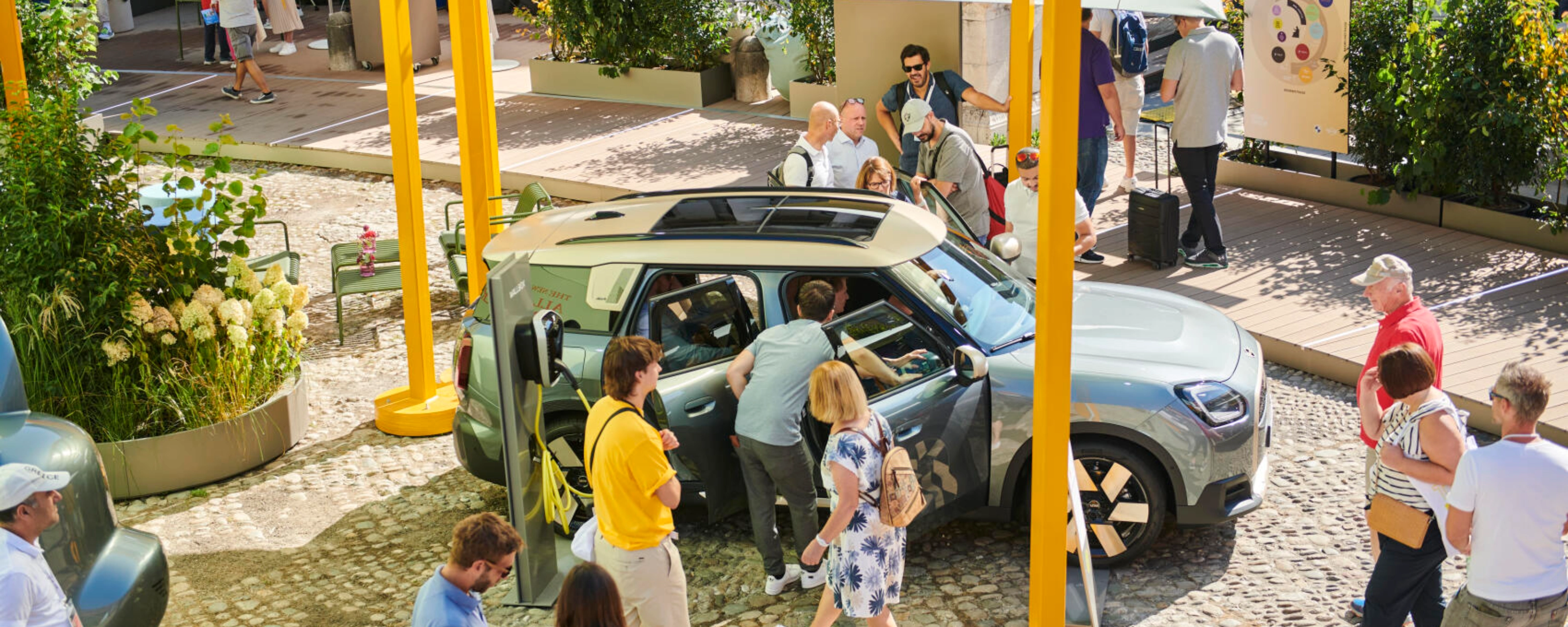 People at an outdoor event looking at a concept car on display.