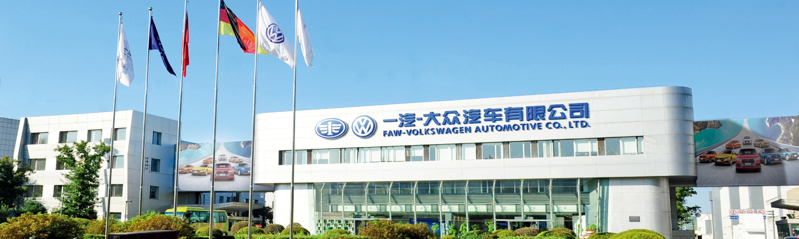 Haupteingang der FAW-Volkswagen Automotive Company mit Fahnen und Firmenschriftzug.