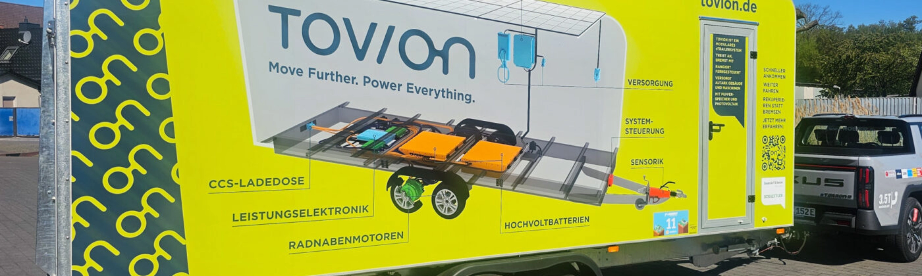 Yellow Tovion trailer with product graphic parked outdoors.