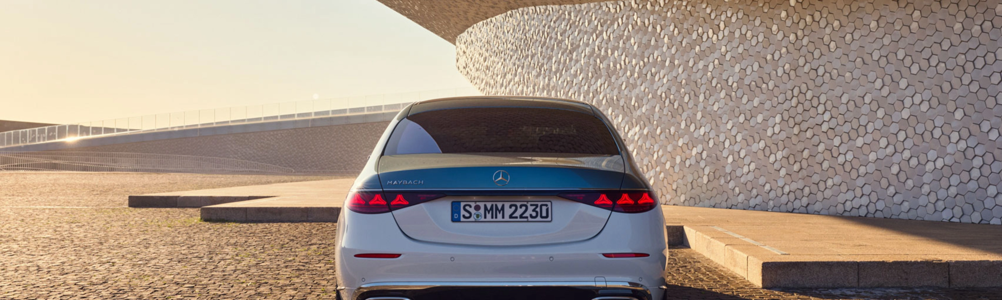 Rückansicht eines weißen Mercedes-Benz vor modernem Gebäude.