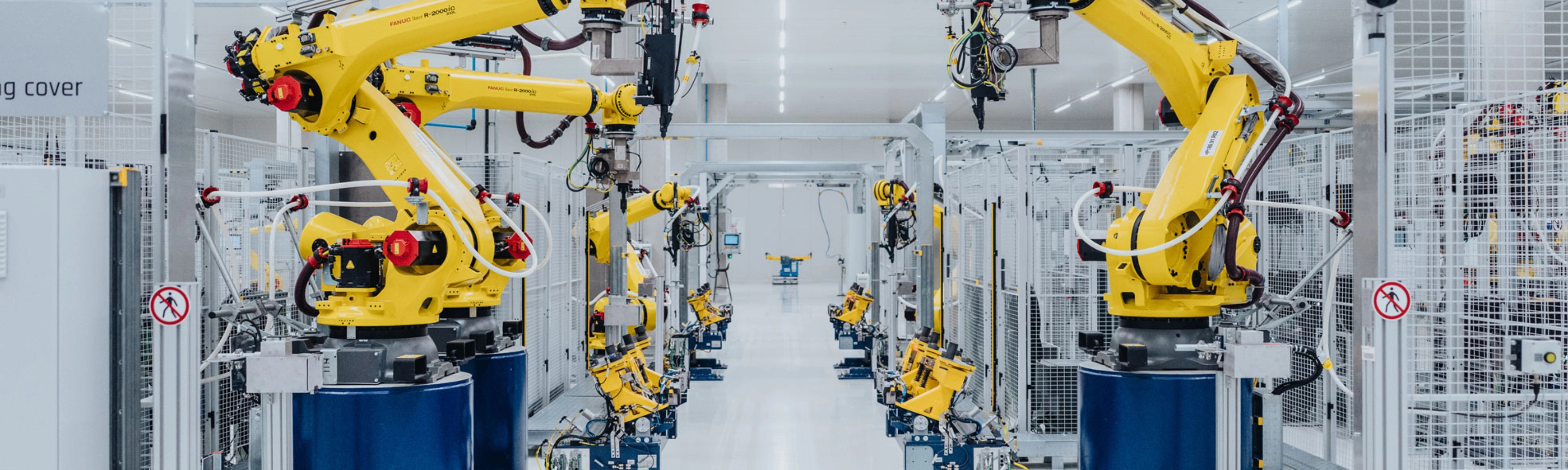 Automatisierte Fertigungslinie mit gelben Industrierobotern in einer Fabrikhalle.